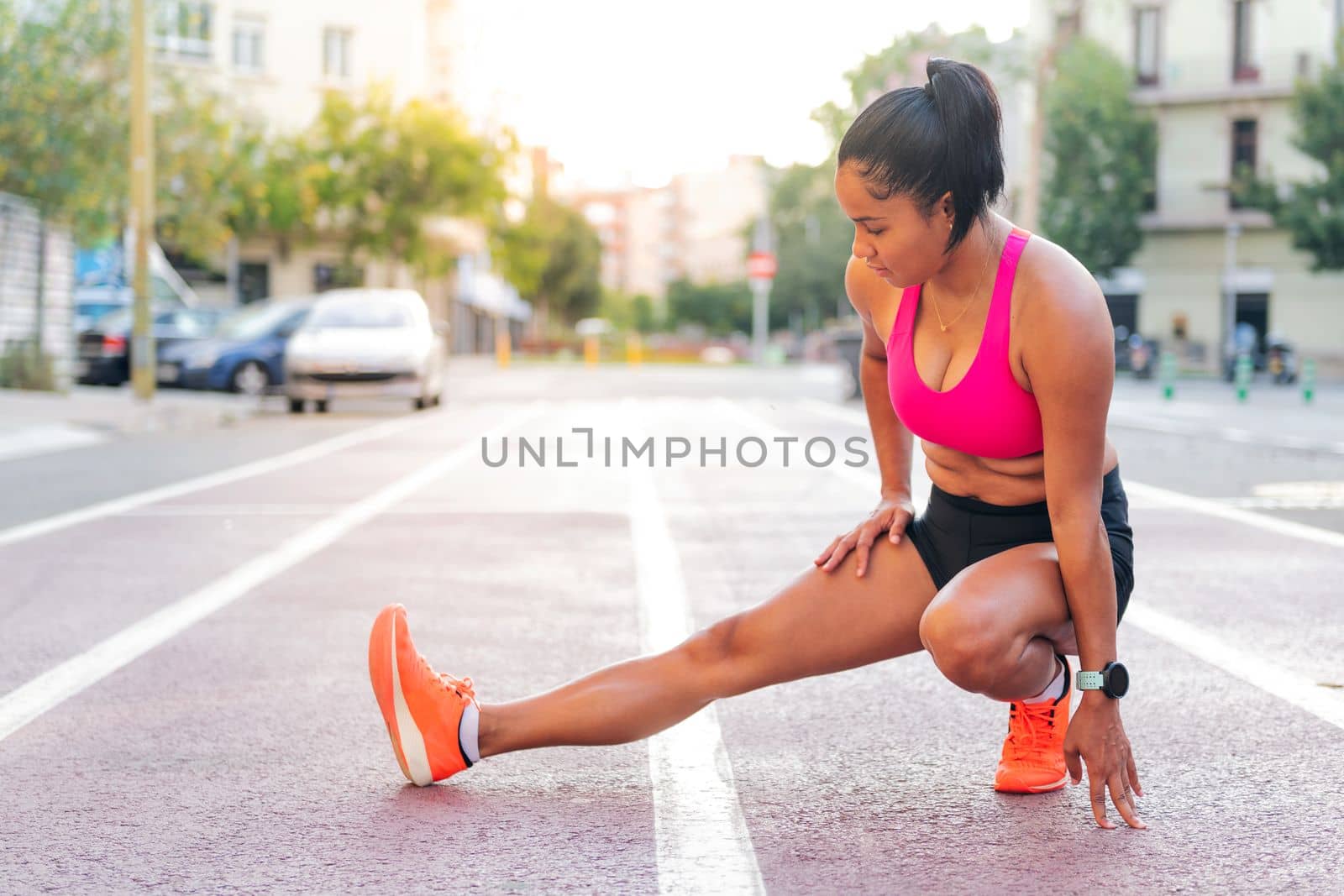 latin sportswoman stretching legs on the athletics track during her training, concept of urban sport and healthy lifestyle, copy space for text