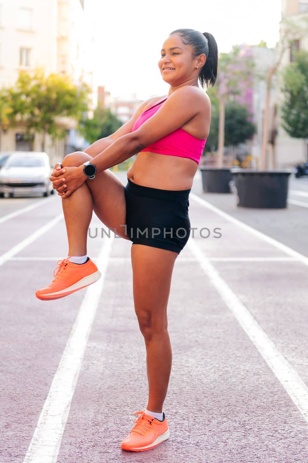 latin sportswoman stretching legs on the athletics track during her workout, concept of urban sport and healthy lifestyle, copy space for text