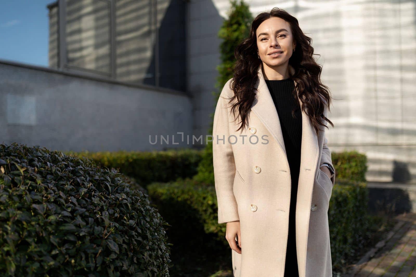 Business woman in beige coat outside by TRMK
