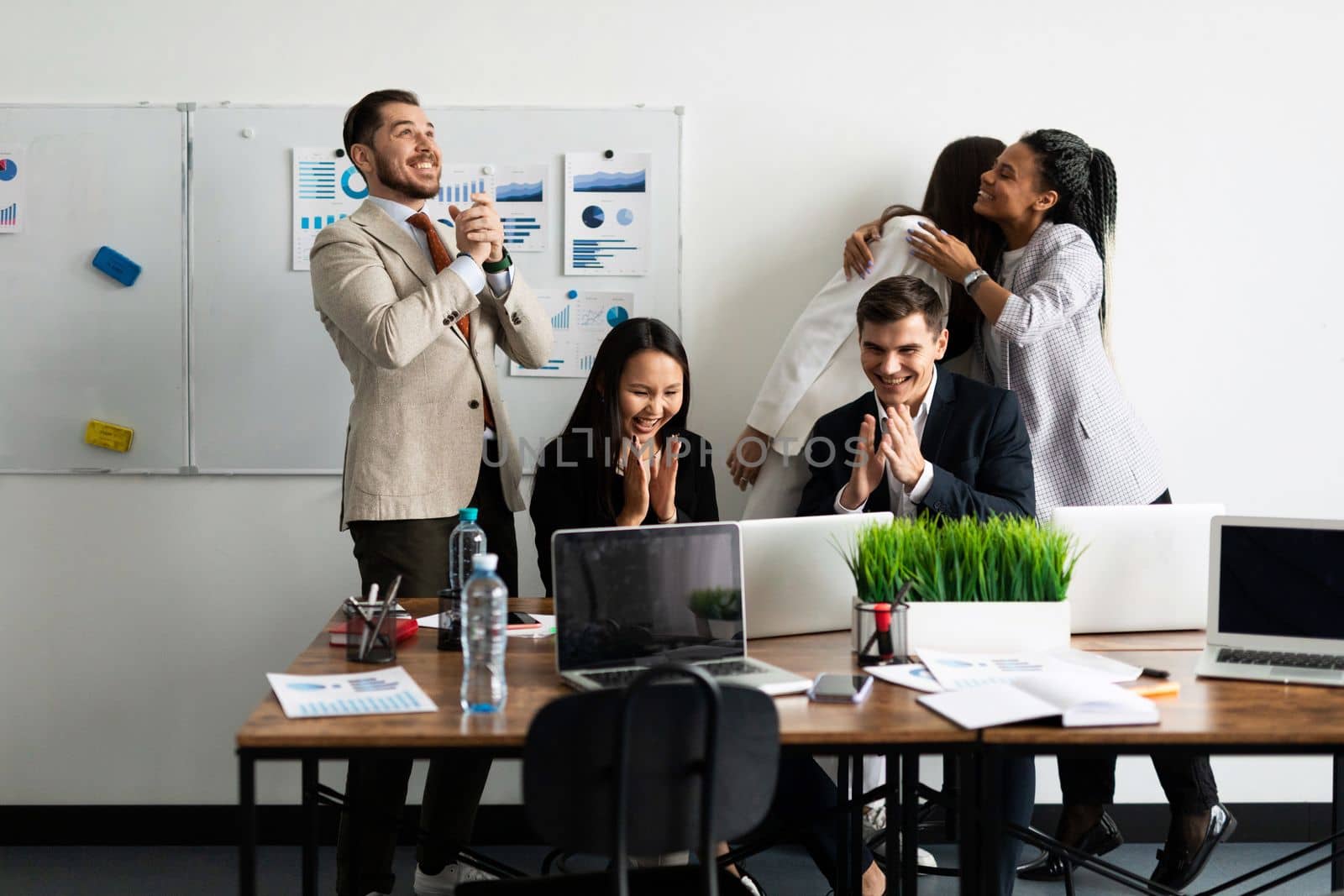 a team of office workers while rejoicing while looking at a laptop monitor.