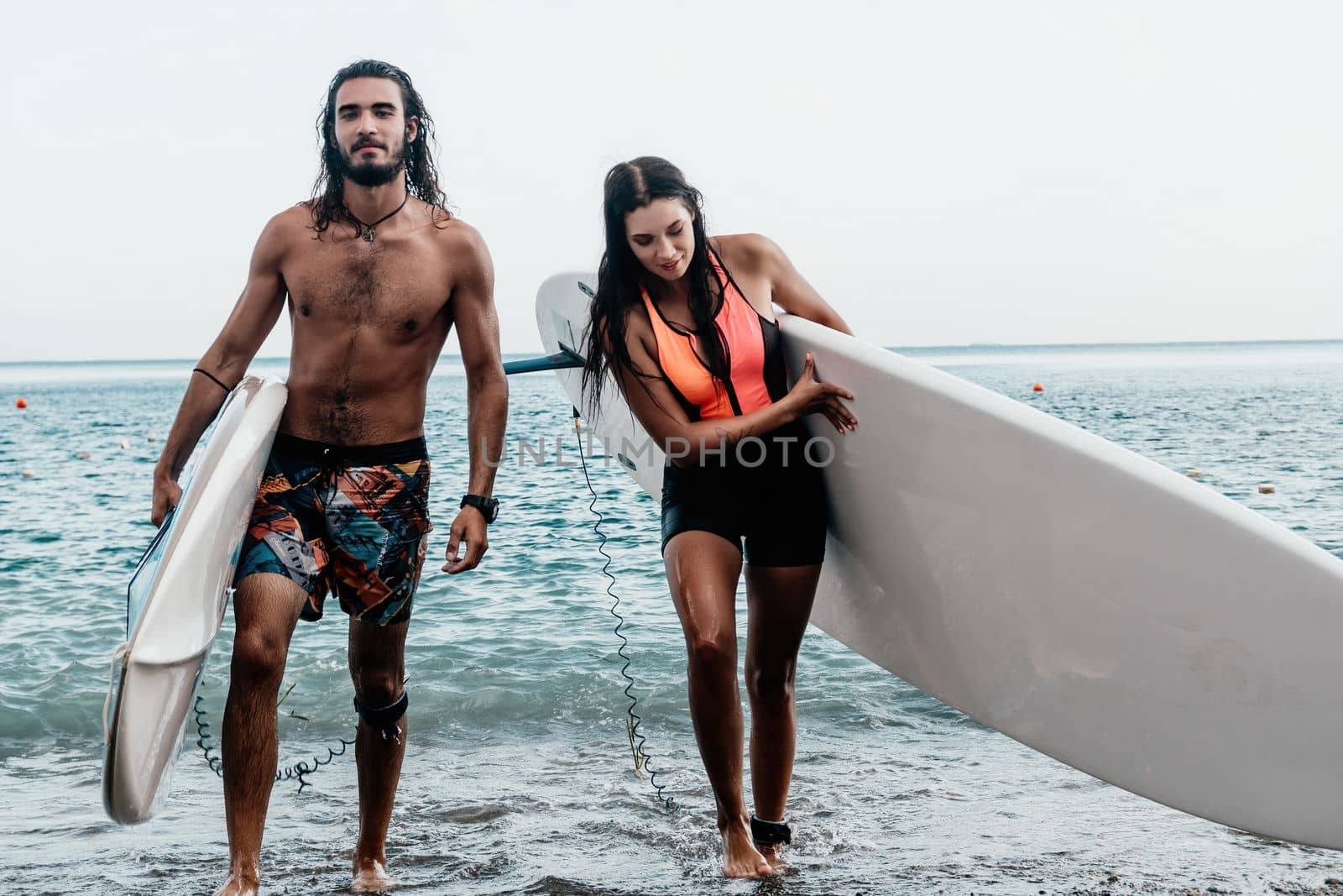 Sea woman and man on sup. Silhouette of happy young woman and man, surfing on SUP board, confident paddling through water surface. Idyllic sunset. Active lifestyle at sea or river