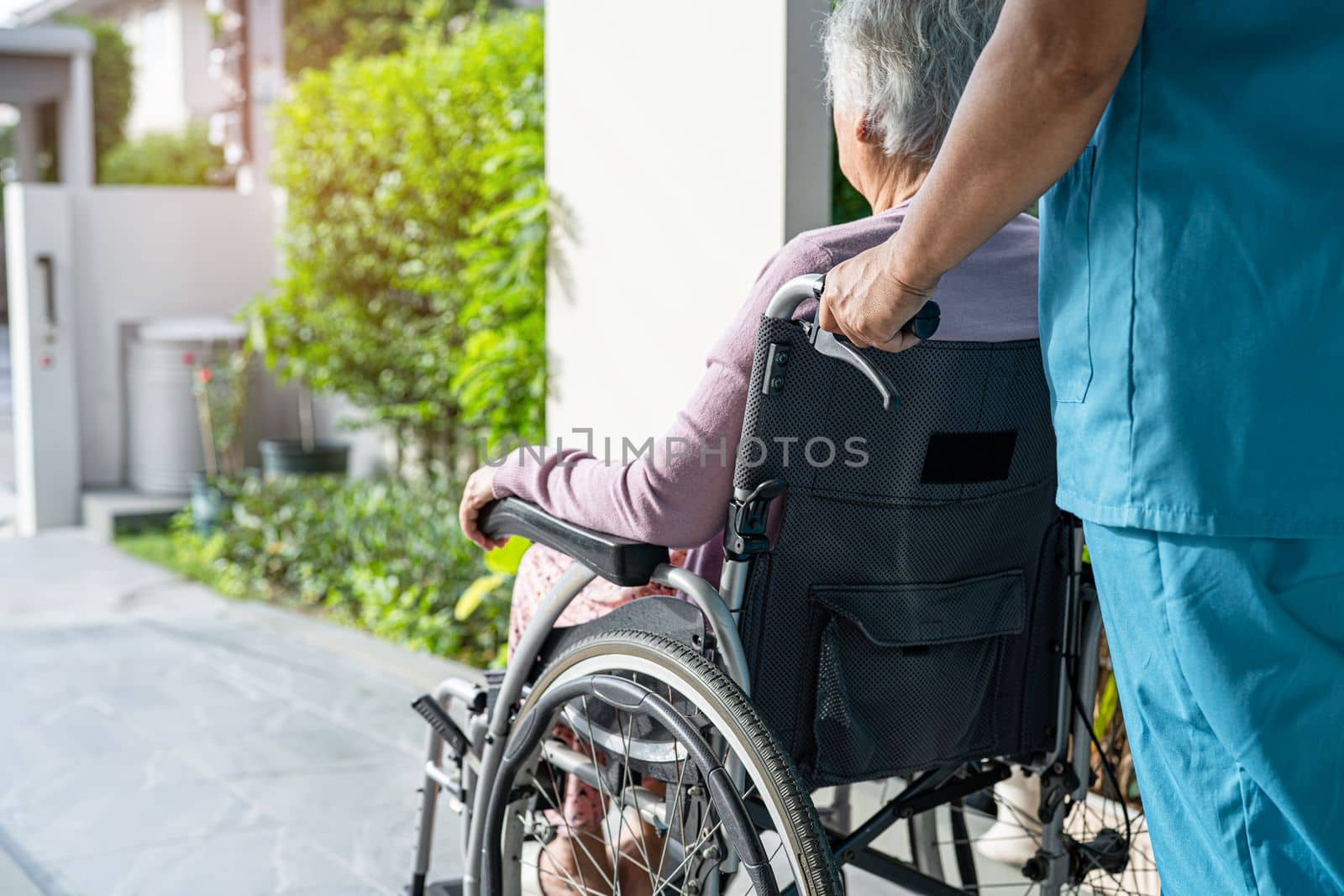 Caregiver help and care Asian senior or elderly old lady woman patient sitting in wheelchair on ramp at nursing hospital, healthy strong medical concept