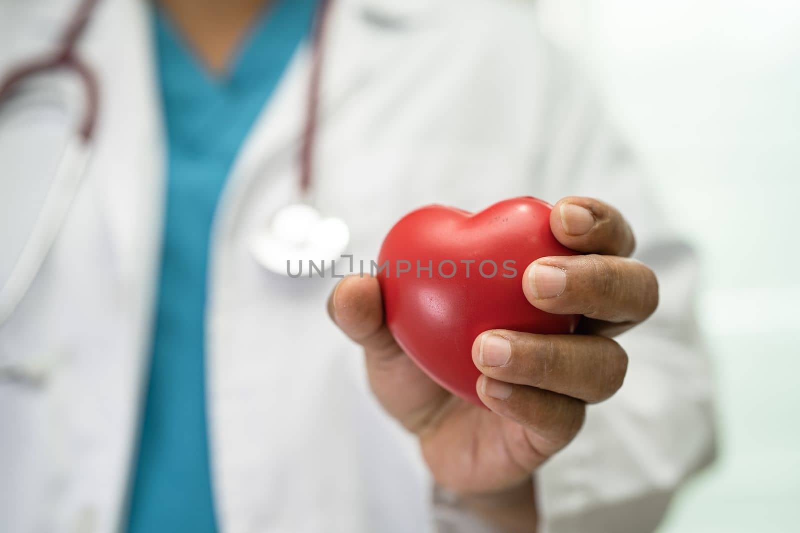 Doctor holding a red heart in hospital ward, healthy strong medical concept.
