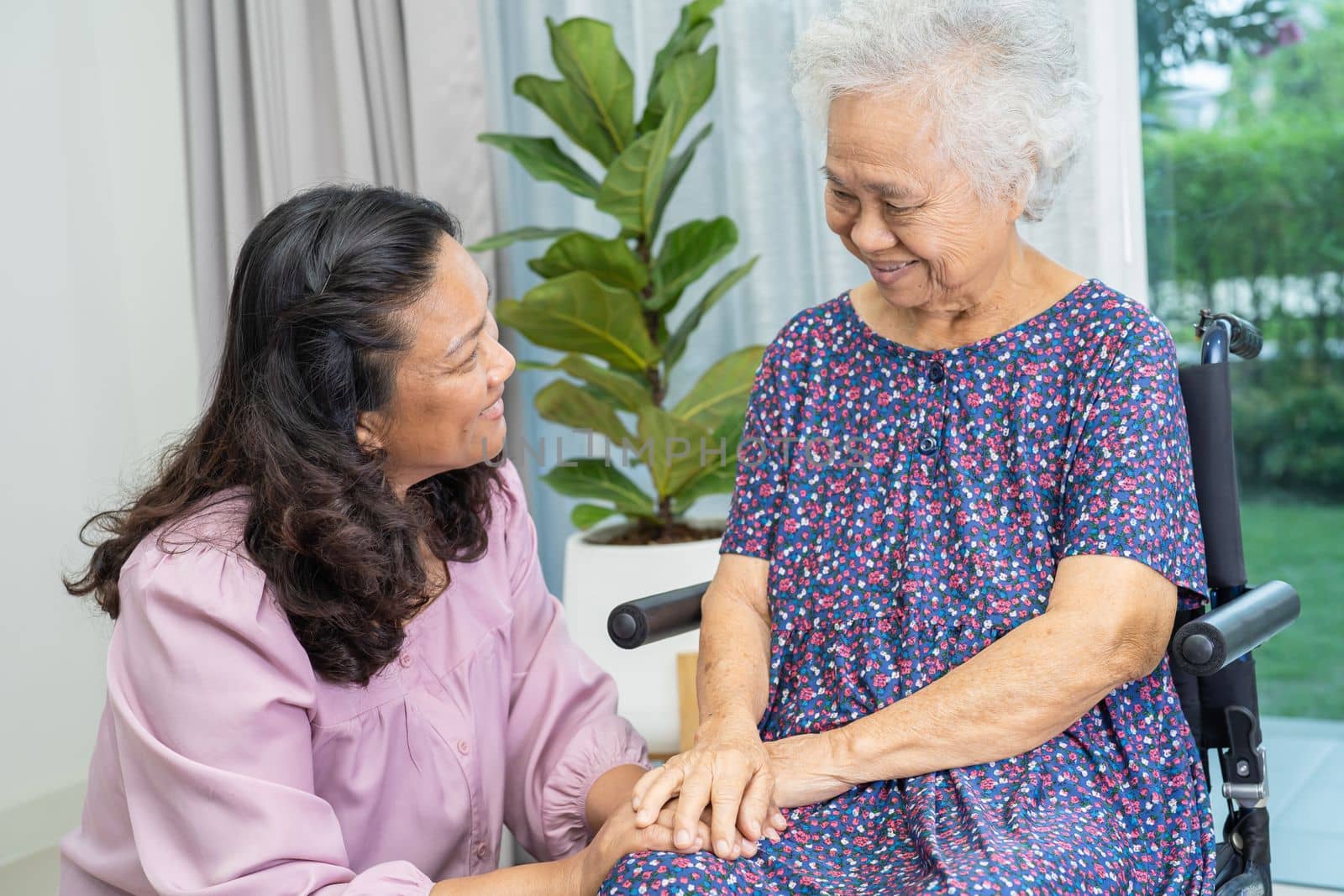 Caregiver help and care Asian senior or elderly old lady woman patient sitting on wheelchair at home.