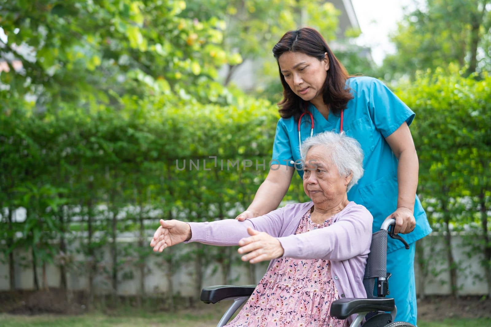 Doctor help Asian senior or elderly old lady woman patient exercise on wheelchair with happy in park. by pamai