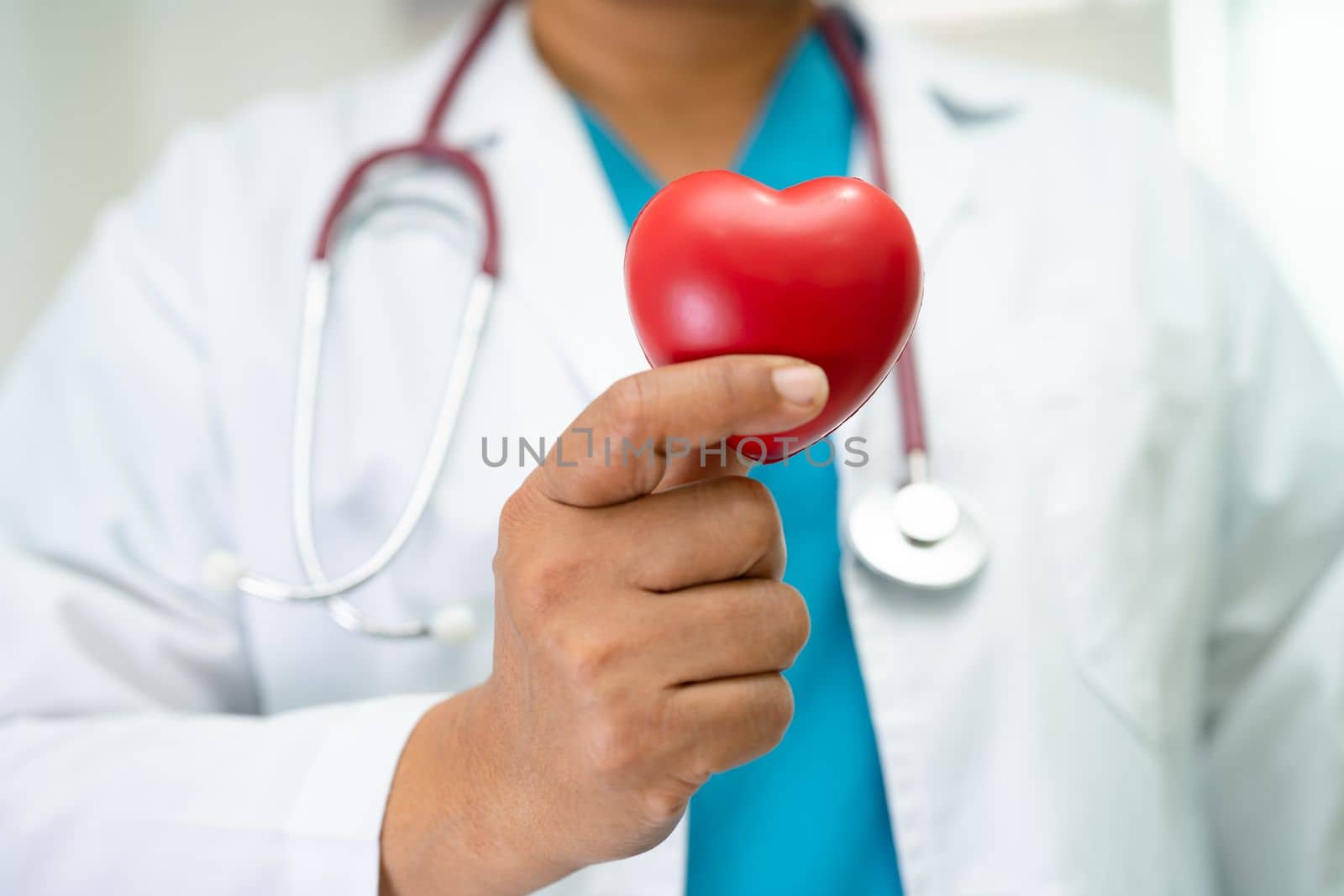 Doctor holding a red heart in hospital ward, healthy strong medical concept.