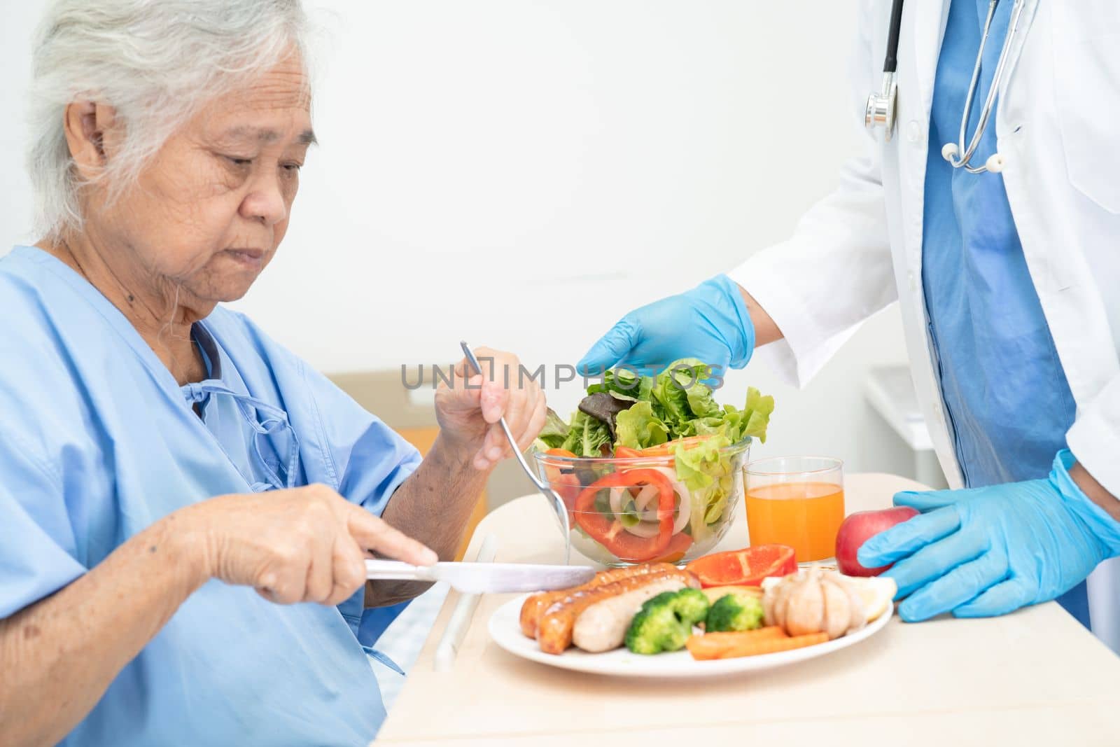 Asian senior or elderly old lady woman patient eating breakfast and vegetable healthy food with hope and happy while sitting and hungry on bed in hospital. by pamai