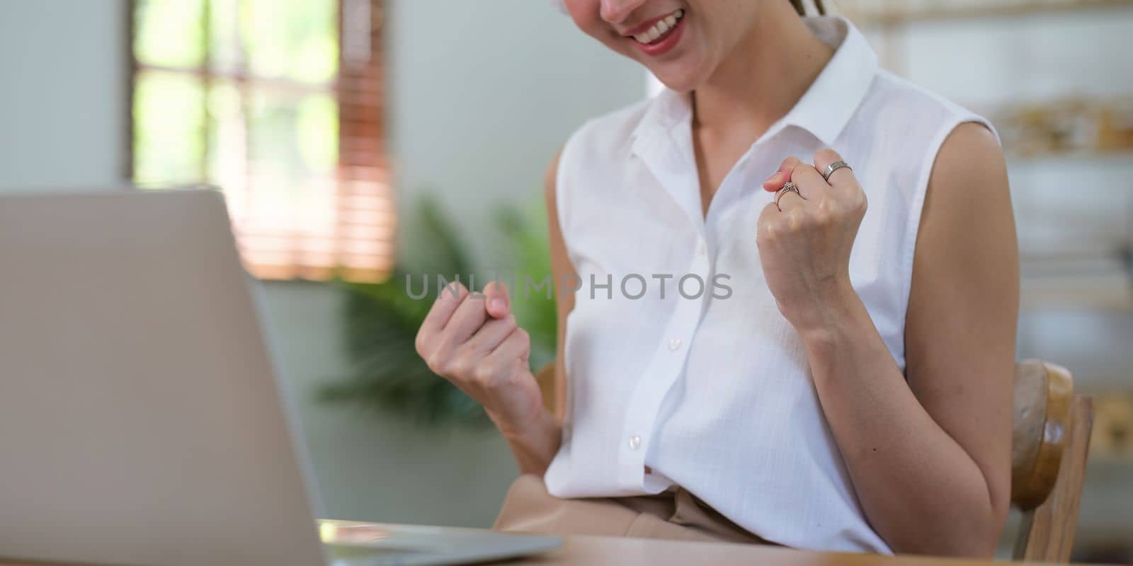 Successful Asian business woman achieving goals. Excited woman screaming with laptop.