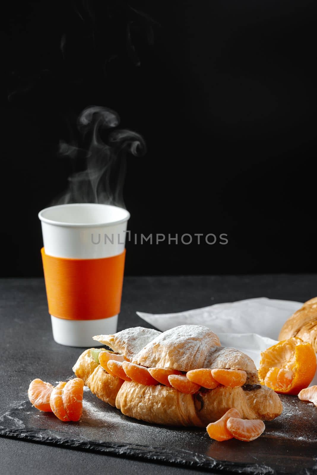 croissant with mandarins sweet on a dark background. Homemade croissants. Falling powdered sugar. Vertical
