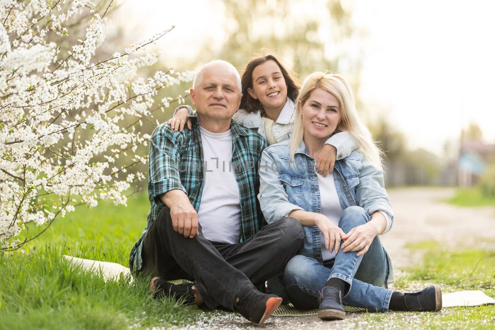 Three generation family sitting outside in spring nature.