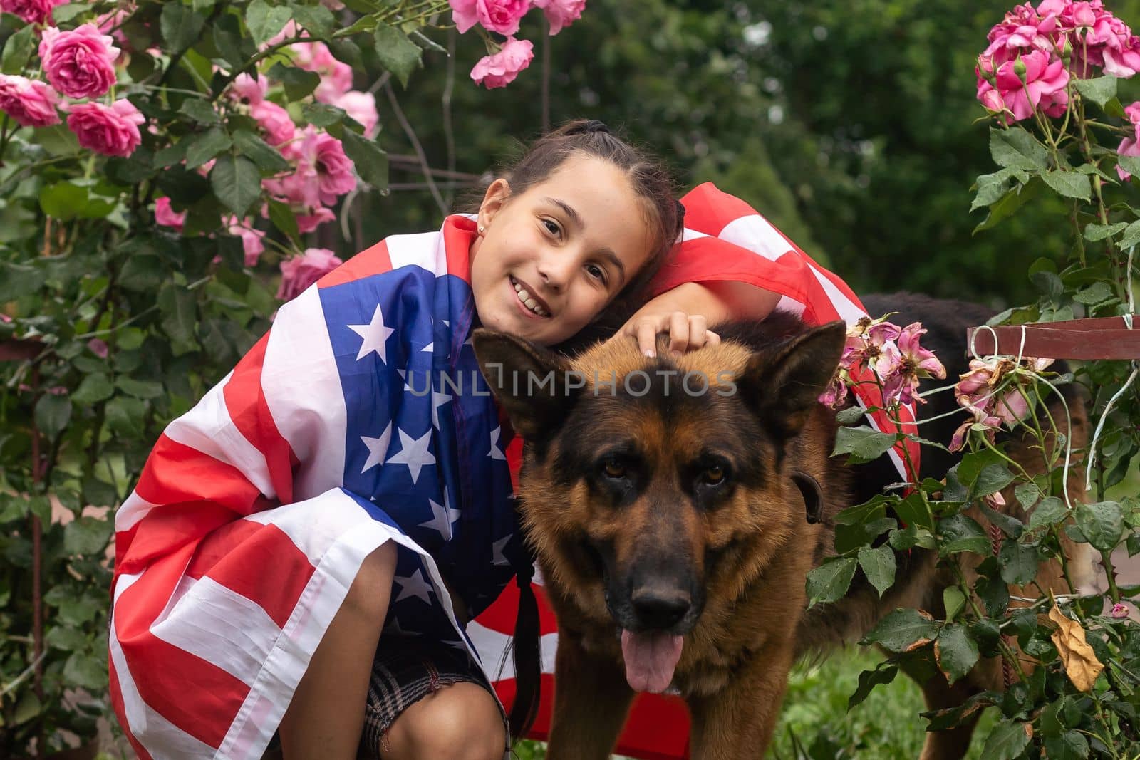 Pretty young pre-teen girl with an American cowboy hat in corn field and the holding American flag. High quality photo