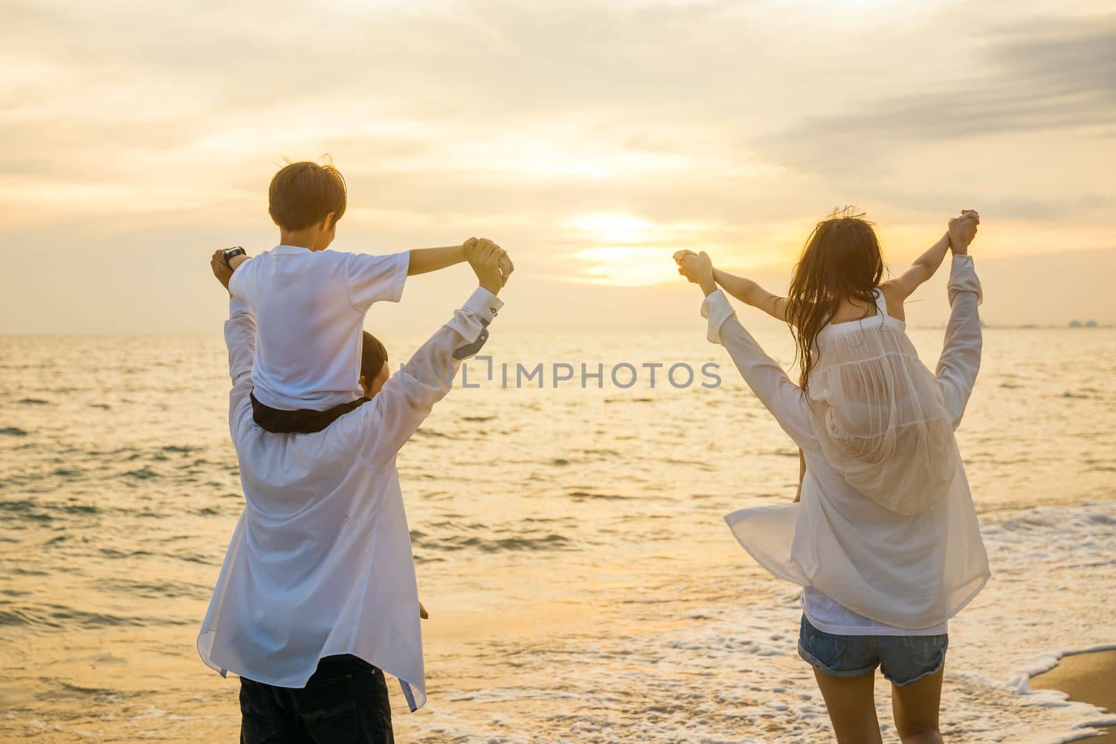 Happy family day. Parents carrying children on shoulders at the beach on sunset time, Father, Mother and kids playing together outdoors on summer beach, Family on holiday summer vacation travel