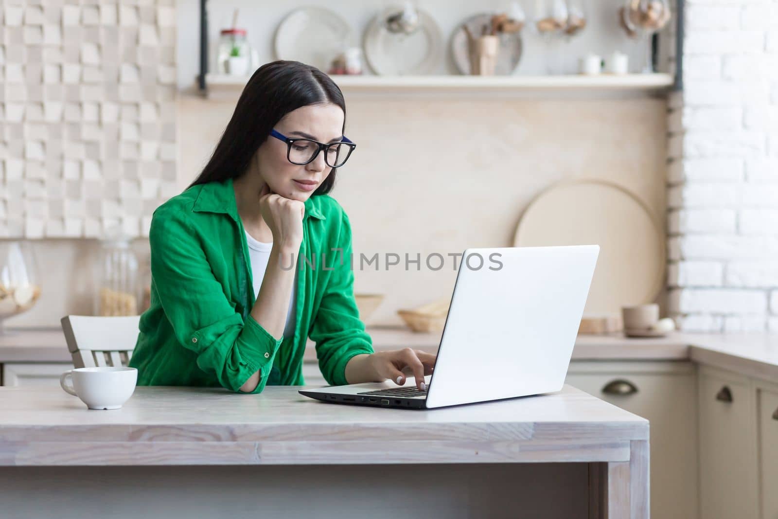 Focused young female designer, engineer, architect working from home online on a laptop by voronaman