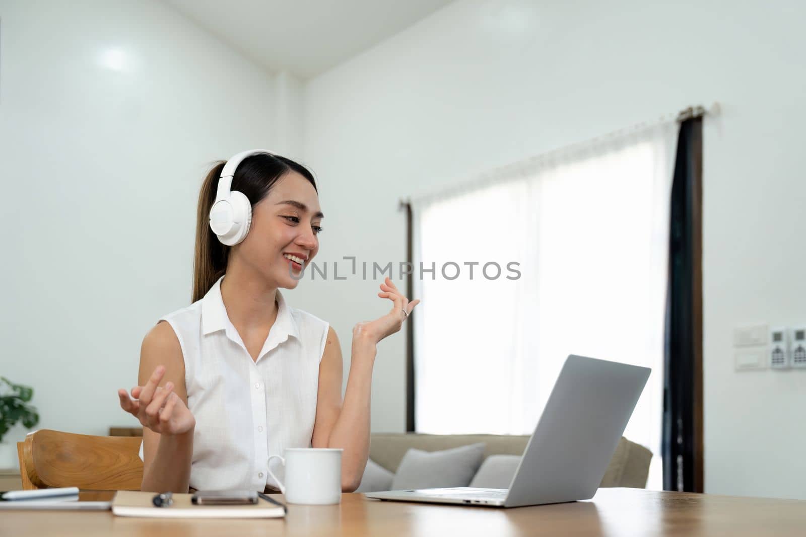 Smiling young asian woman working on laptop at home. Attractive asia female using computer remote studying, watching online education and video calling for webinar