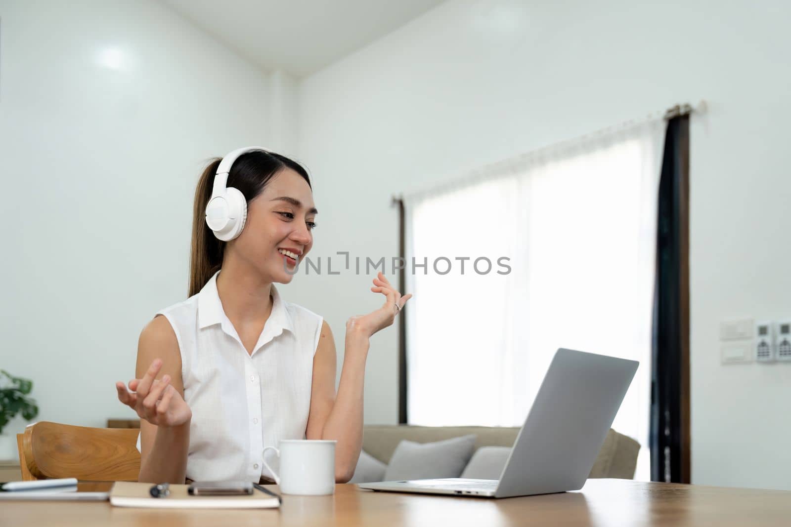 Smiling young asian woman working on laptop at home. Attractive asia female using computer remote studying, watching online education and video calling for webinar. by nateemee