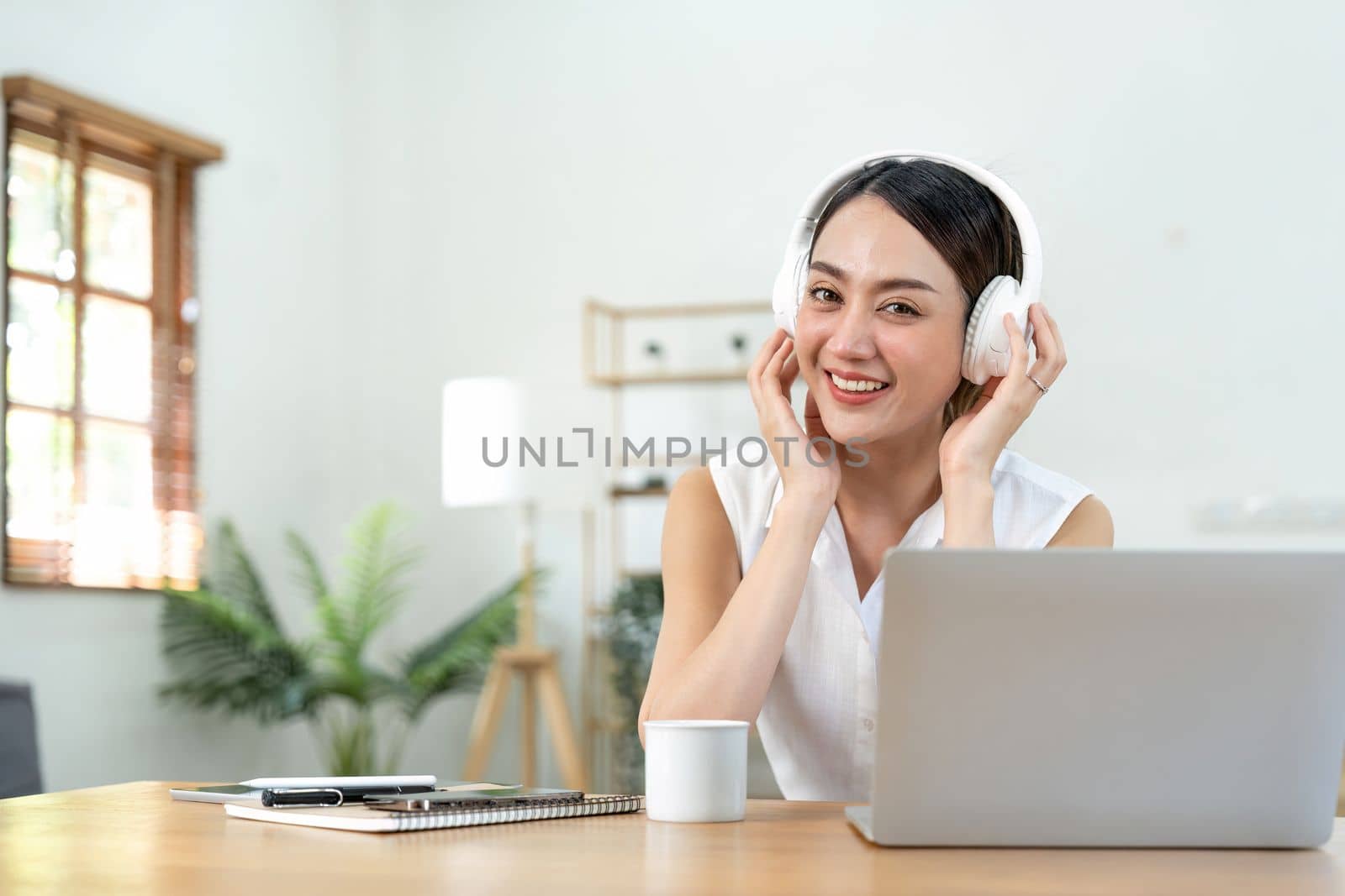 portrait of young smiling asian woman in headphones listening to music at home by nateemee