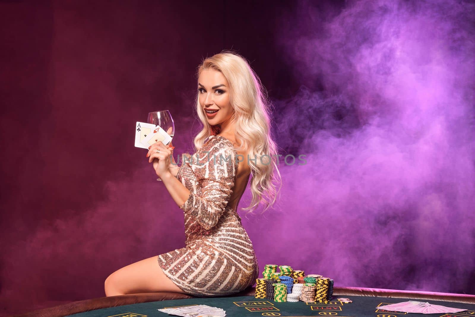 Blonde woman with a perfect hairstyle and bright make-up is posing with playing cards in her hands. Casino, poker. by nazarovsergey