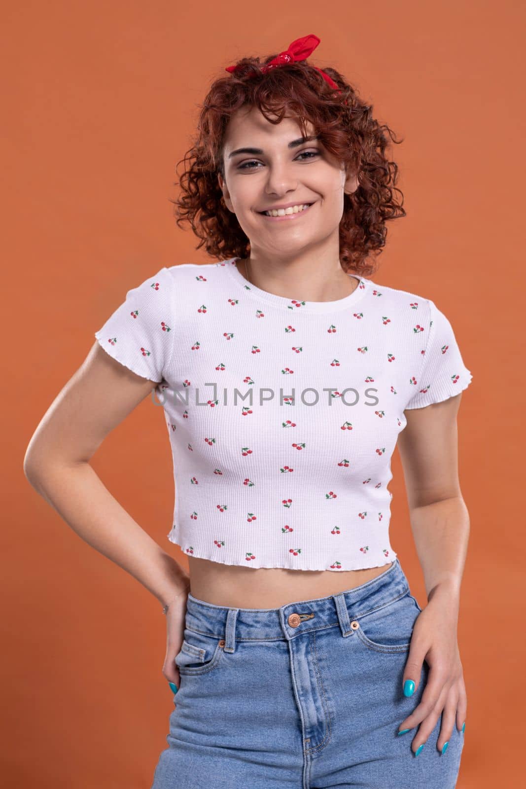 Attractive young girl with a beautiful smile one hundred and one brick-colored background. White blouse with cherry pattern.