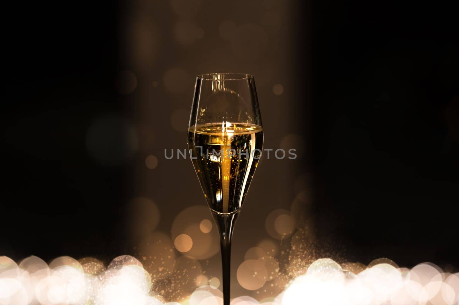 Glass of champagne with bubbles on dark background with bokeh. Celebration and party concept. by DariaKulkova