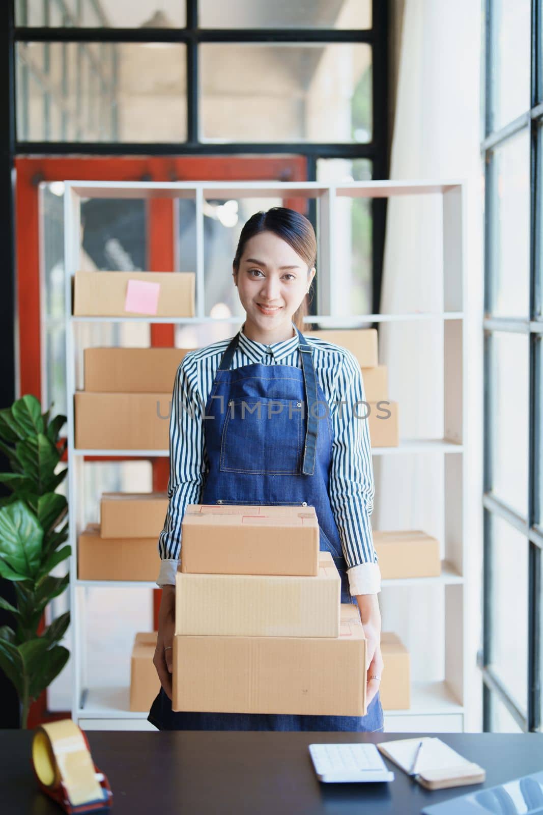 Starting small business entrepreneur of independent Asian female online seller packing products to send to customers and SME delivery concept.