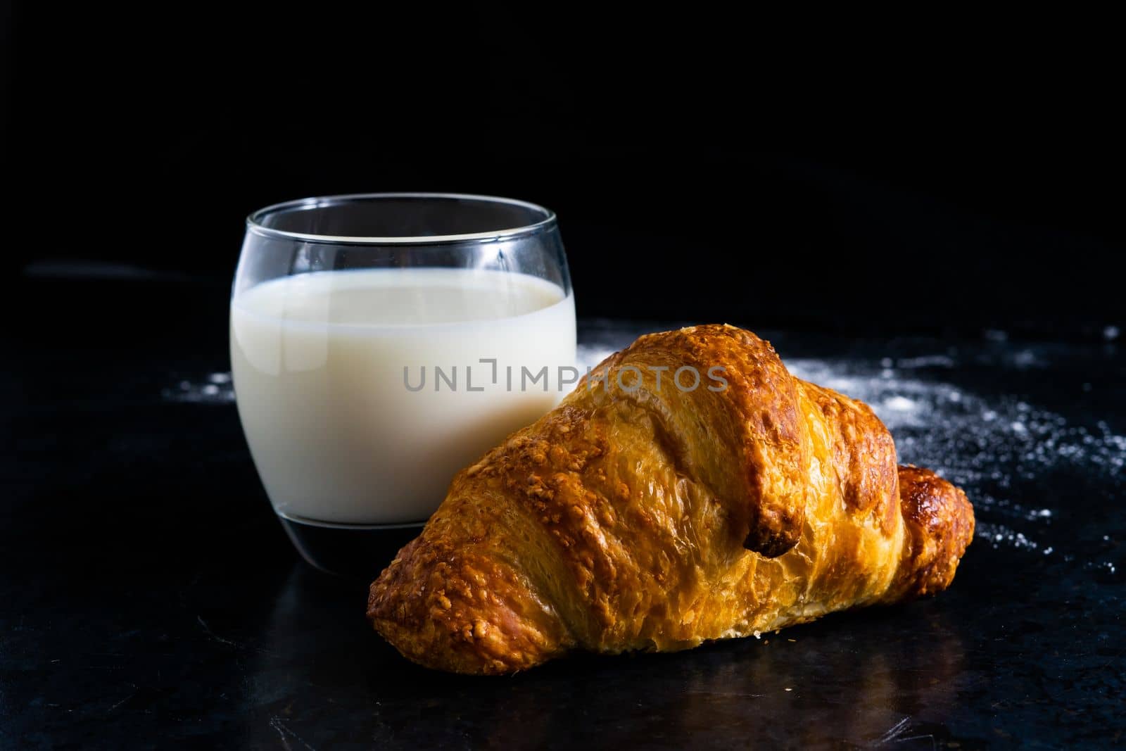 Fresh white bread and milk in white glass on black stone table background. Top view Studio shot