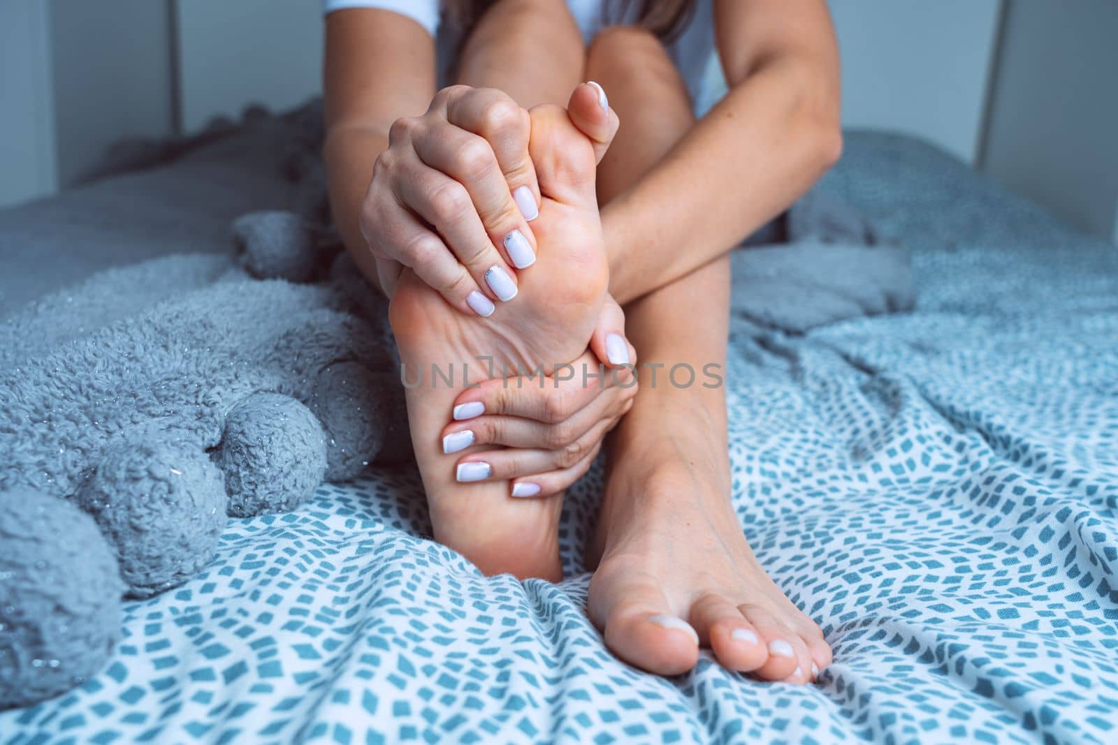 Woman suffering from feet pain or feet ache and massaging painful foot. Leg cramps, pain in legs or muscle spasm by DariaKulkova