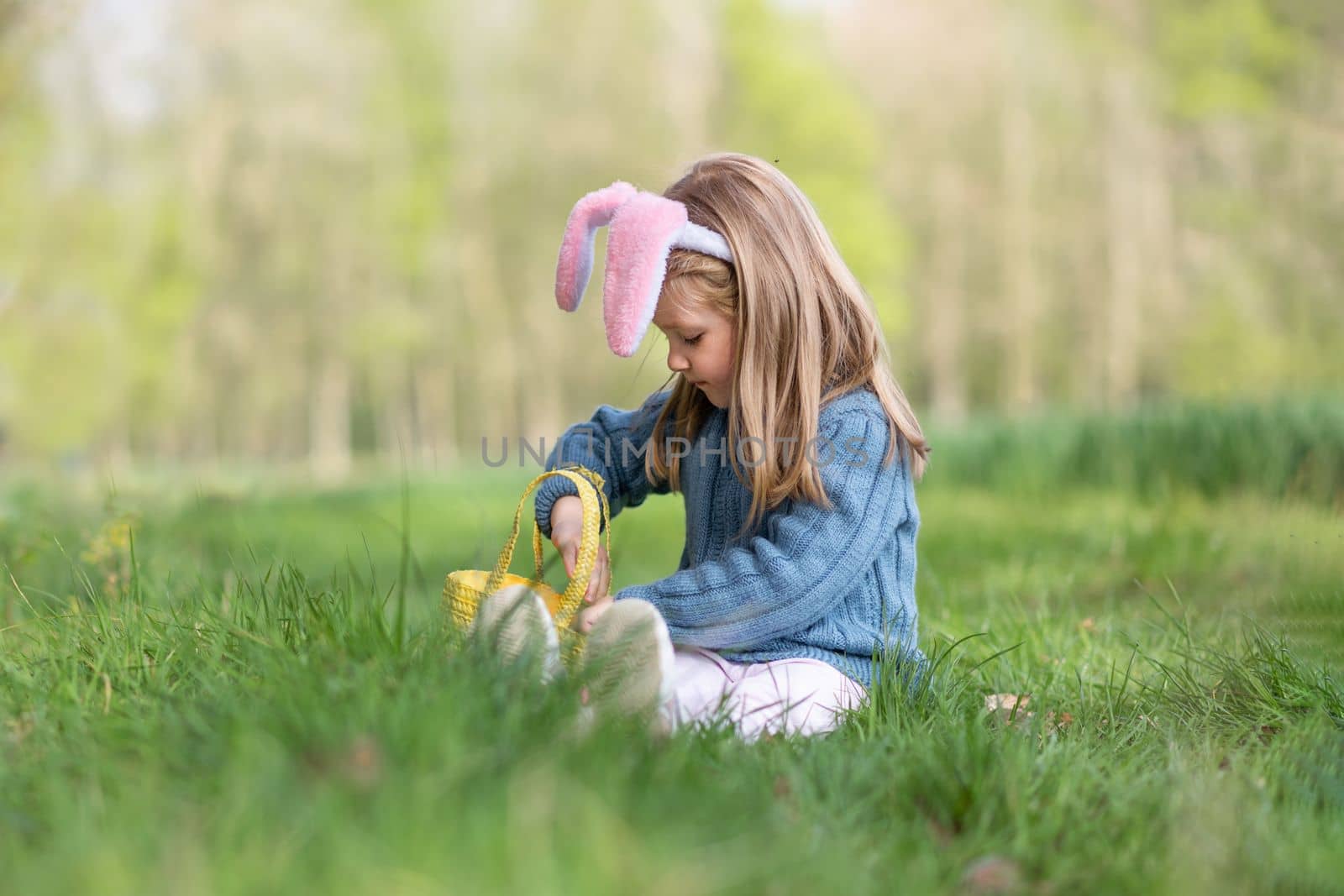 Girl with bunny ears collects the eggs in a basket for Easter
