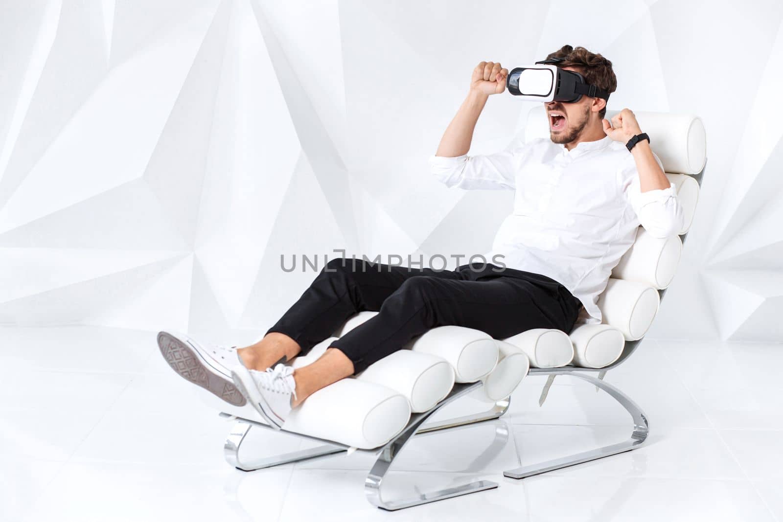 Excited young man is getting experience using VR-headset glasses of virtual reality gesticulating with his hands by nazarovsergey