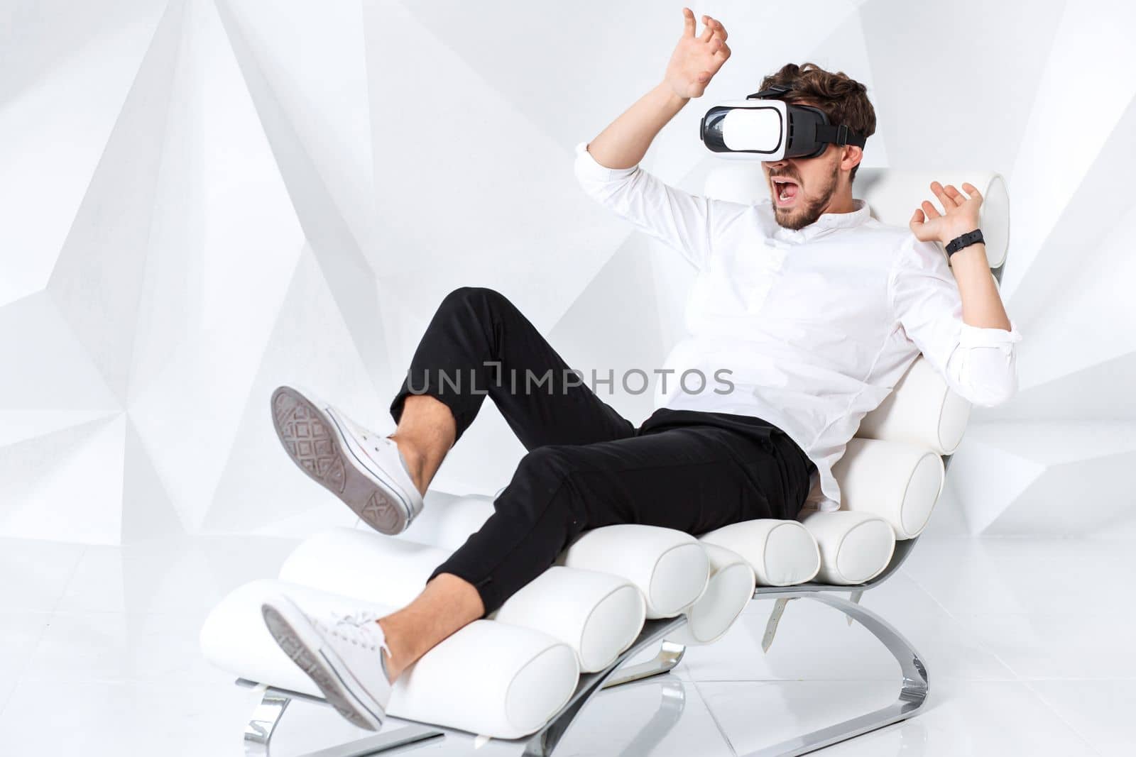 Excited young man is getting experience using VR-headset glasses of virtual reality gesticulating with his hands by nazarovsergey