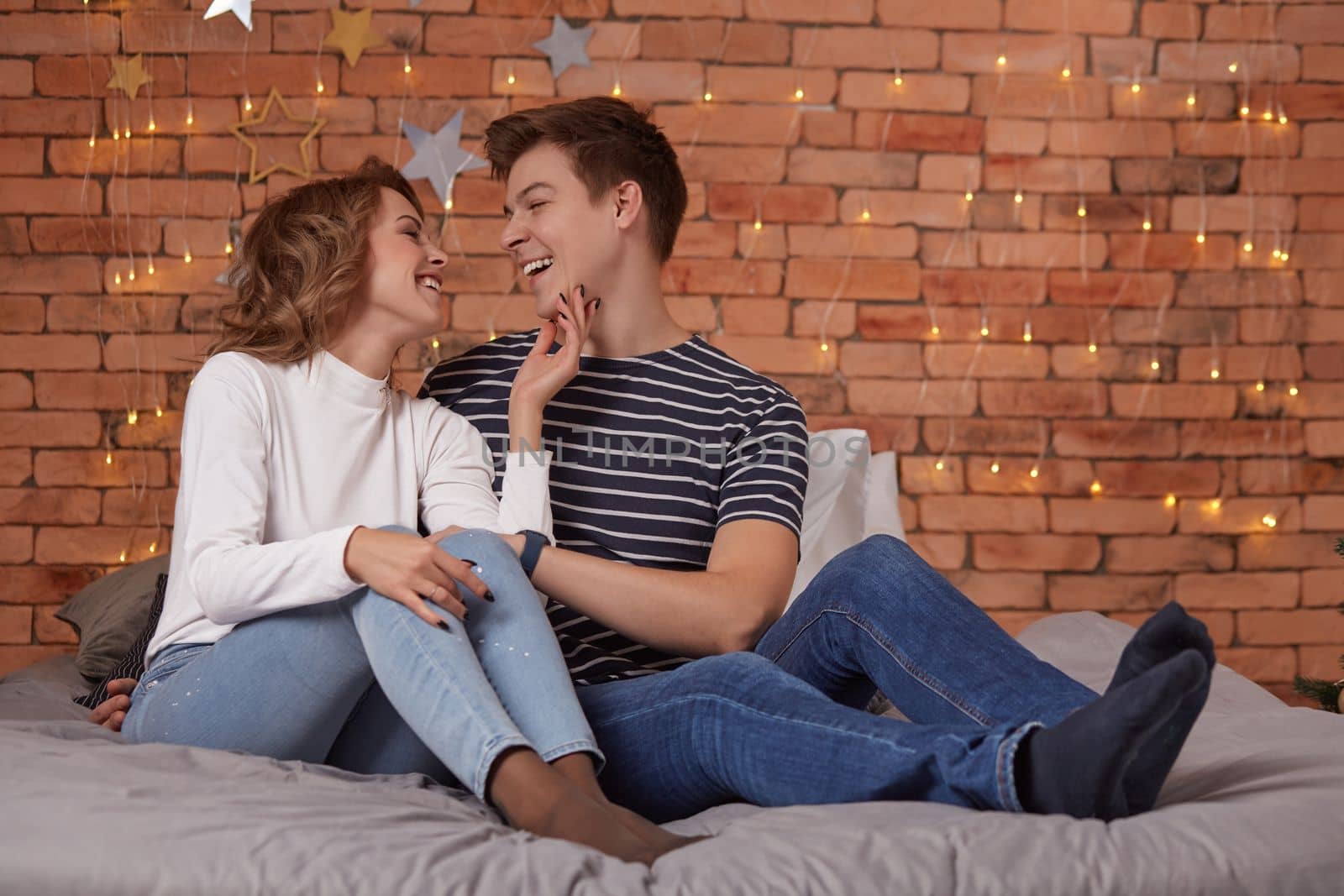 Young man and woman tenderly embracing in bedroom on the bed, they show tenderness to each other