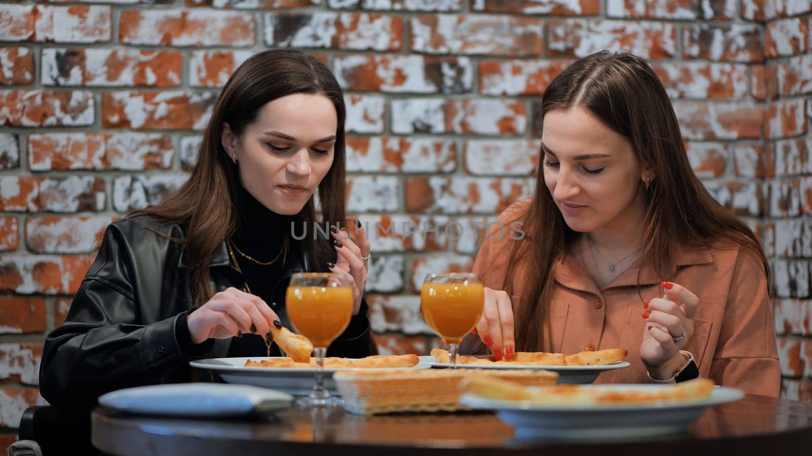 Young girls eat in a cafe and feed each other. by DovidPro