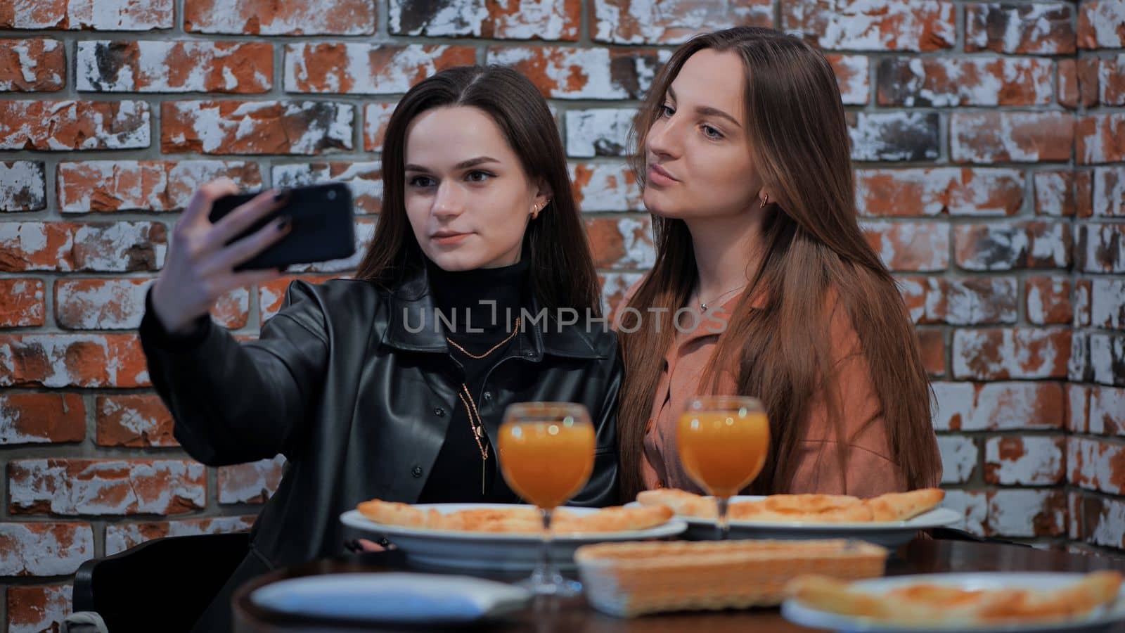 Two girls are sitting in a cafe and taking a selfie on the phone