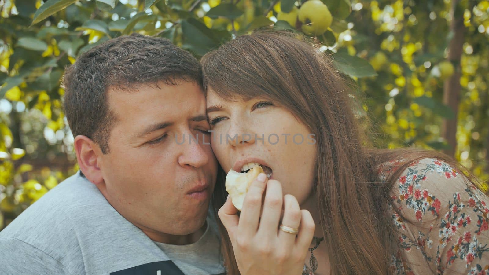 A couple in love eating apples in the orchard