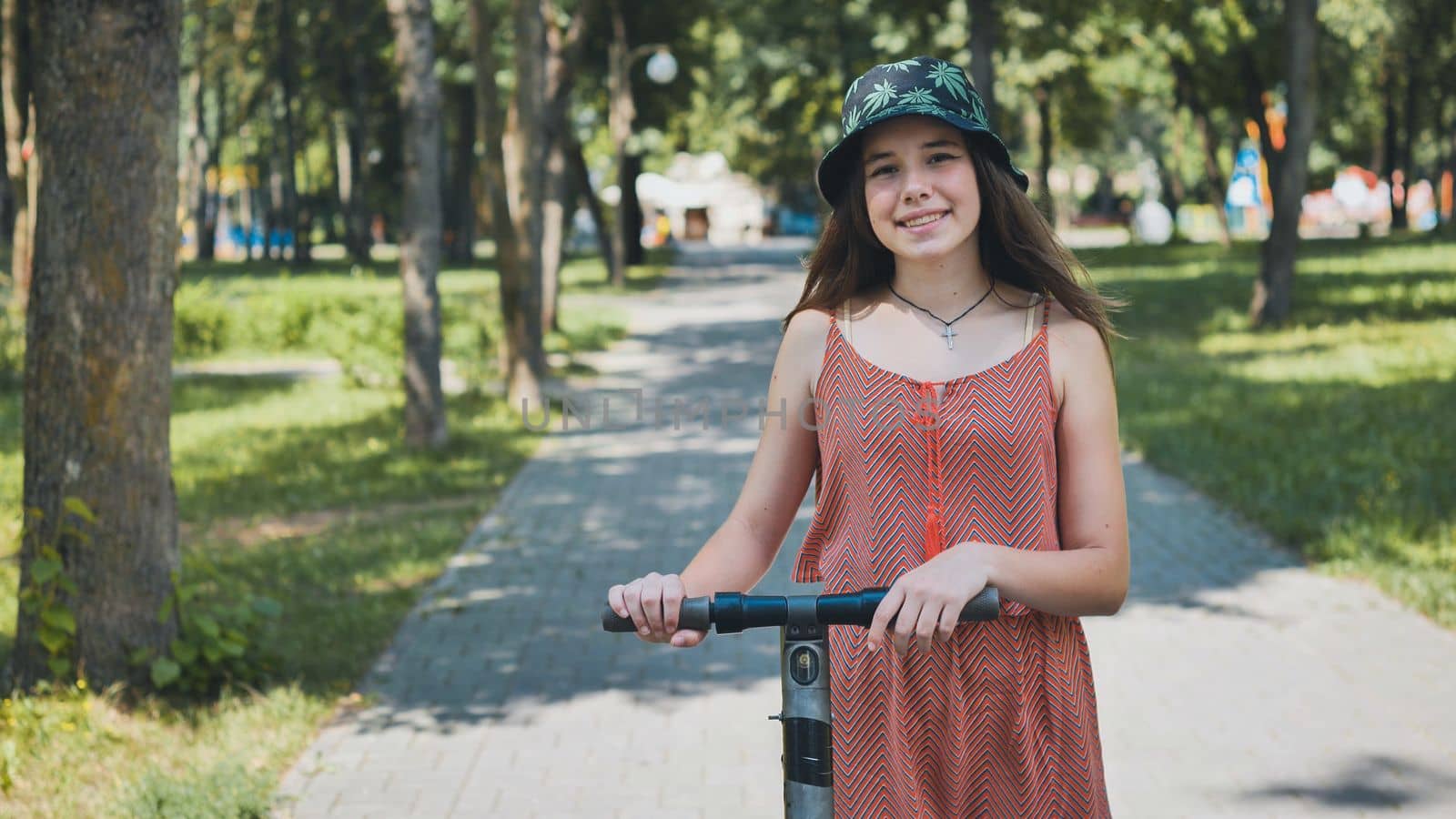 Portrait of a girl on an electric scooter posing in a park in the summer