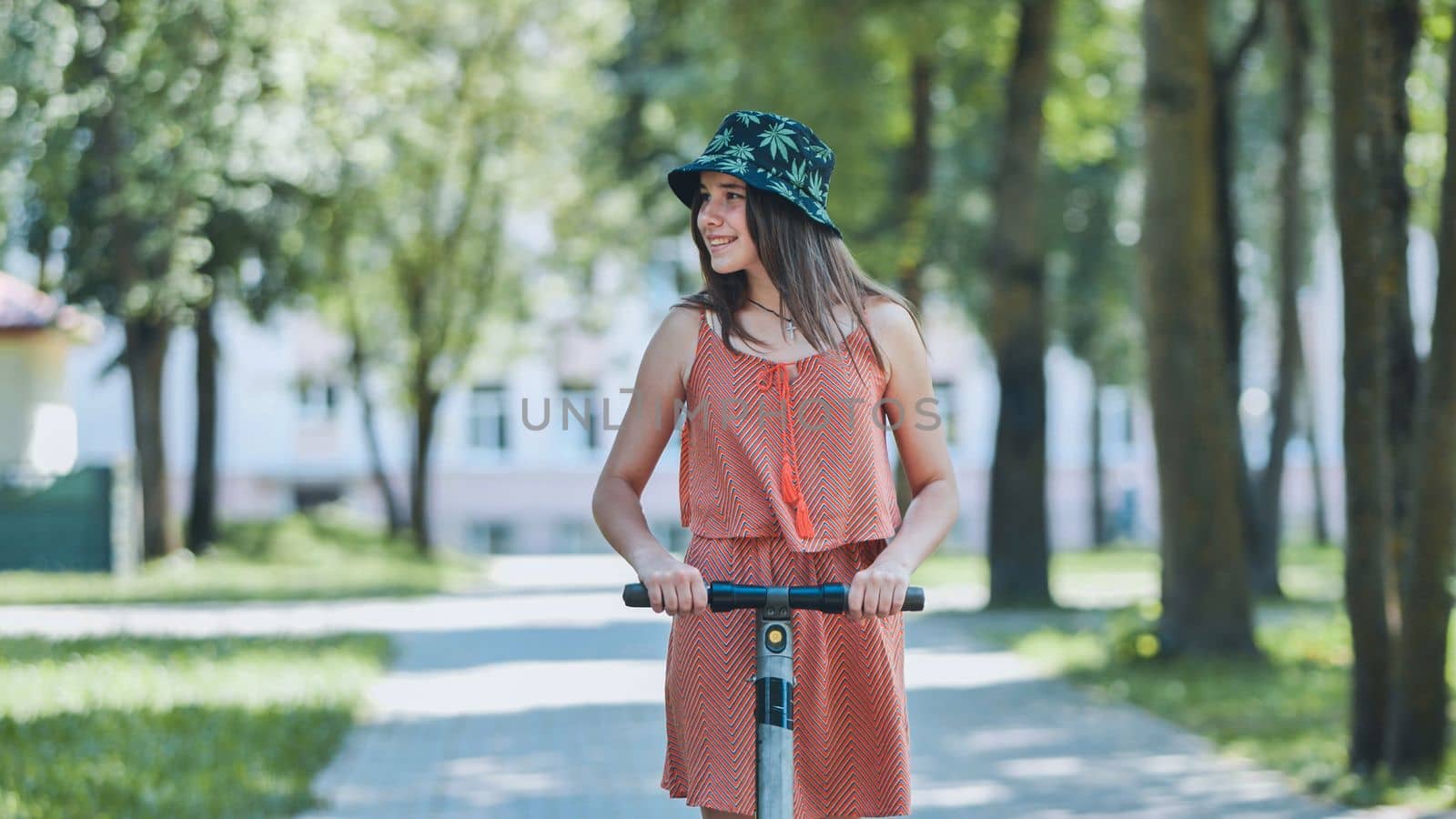 Portrait of a girl on an electric scooter riding in a park in the summer