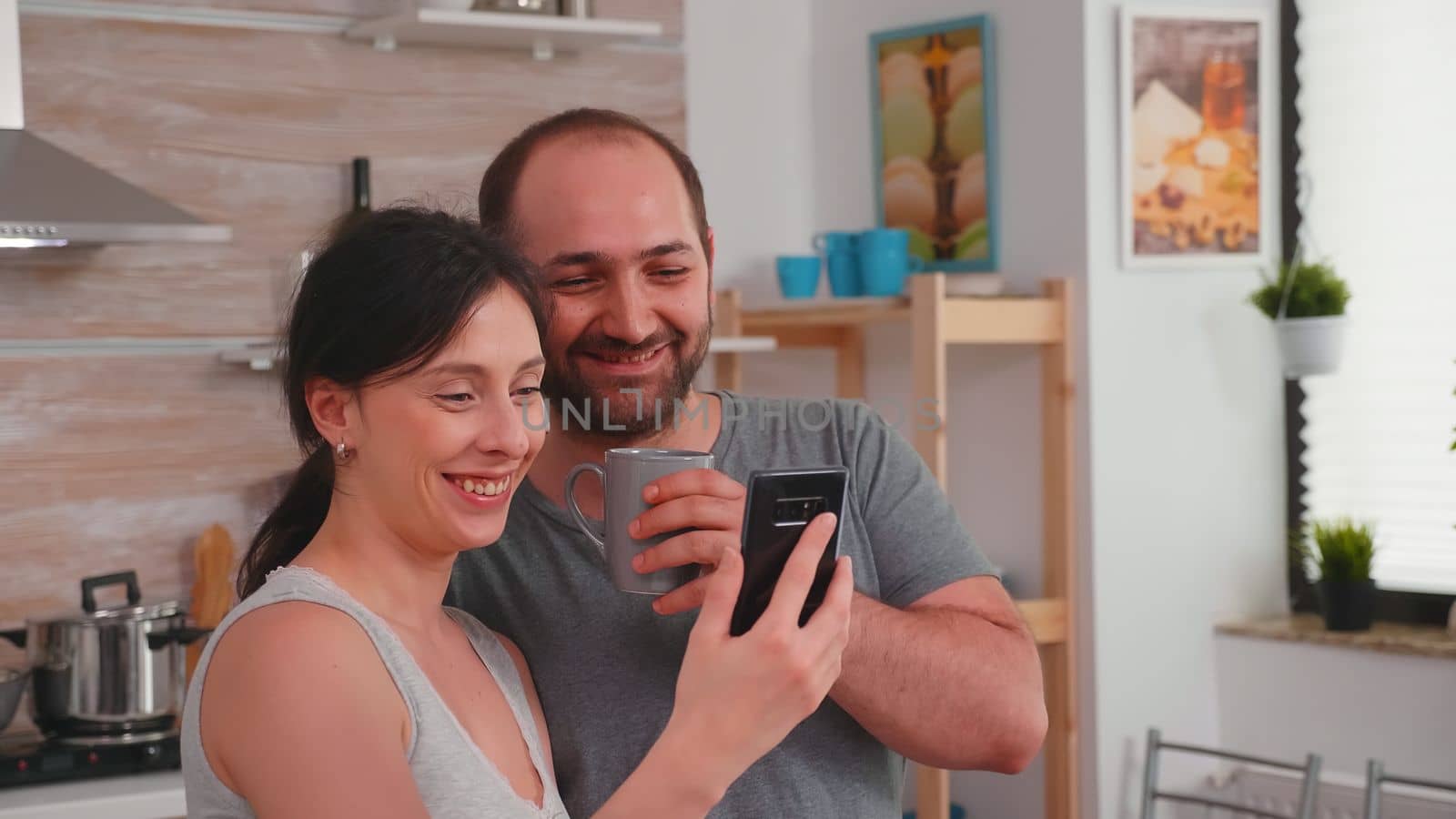 Authentic couple in the morning smiling and looking at phone by DCStudio