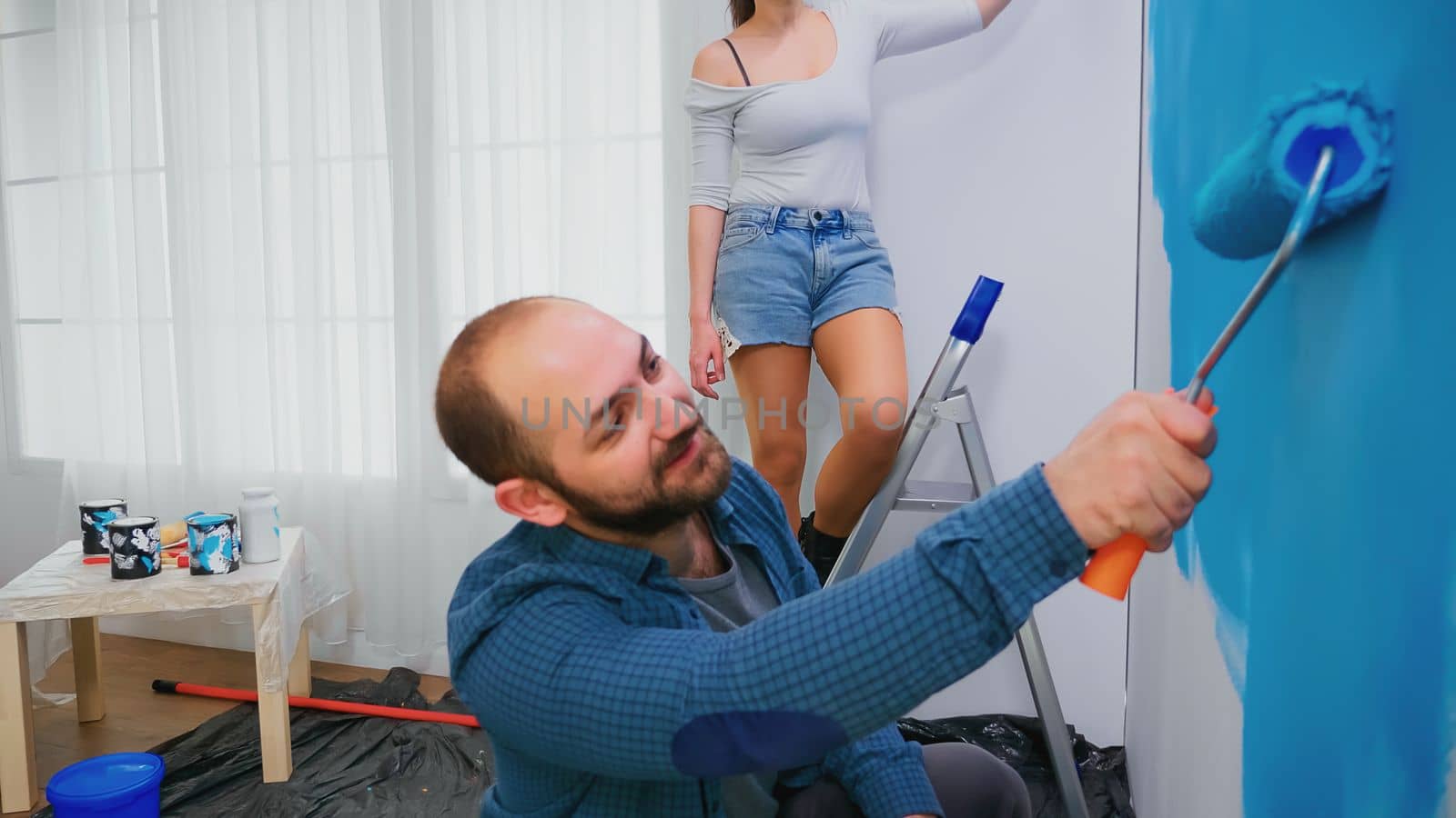 Wife painting wall on ladder by DCStudio