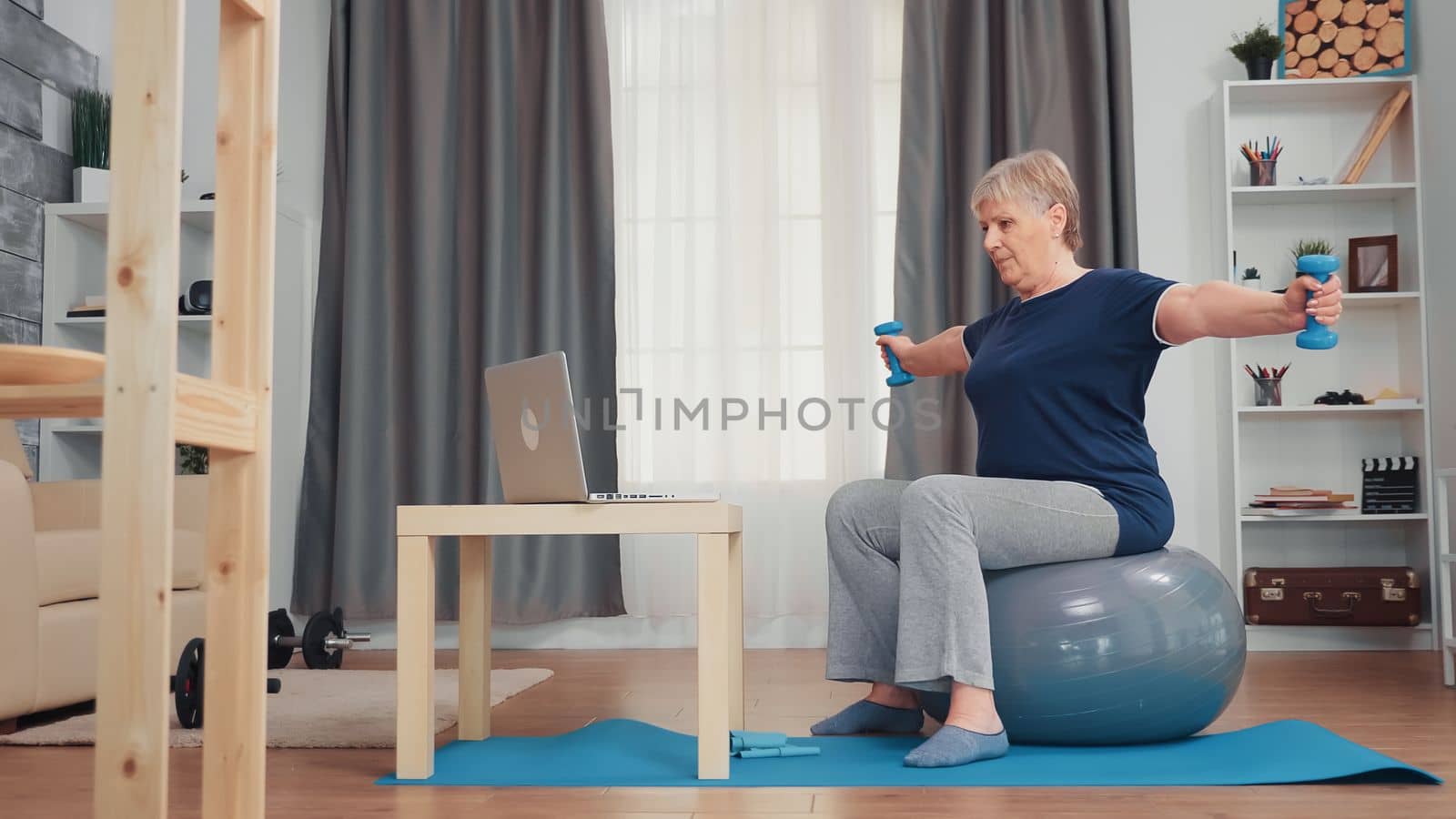 Healthy senior woman exercising with dumbbells in living room. Old person online internet training at home sport healthy lifestyle, elderly fitness exercise workout in apartment, activity and healthcare