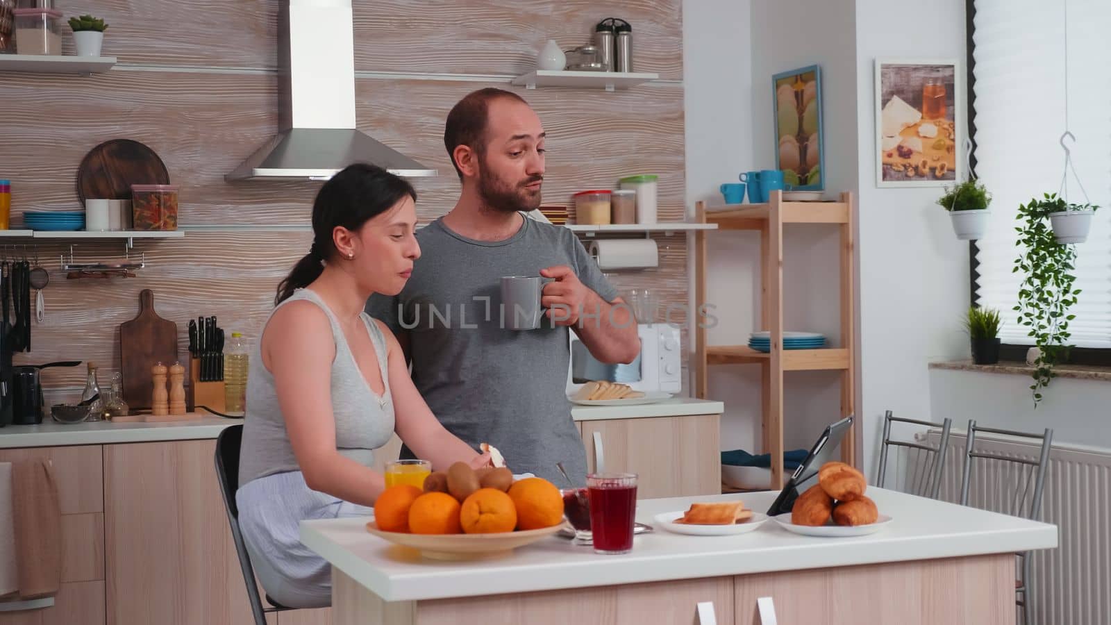 Couple talking online with family on a video call during breakfast. Videoconference in the morning, using online web internet technology, talking and communicating with relatives