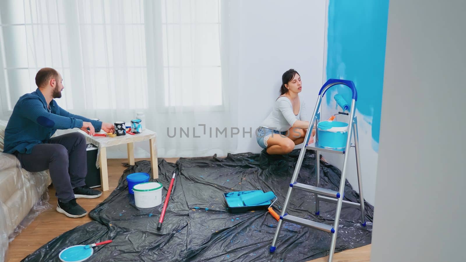 Couple redecorating apartment. Changing wall color. Painting with roller brush. Couple in home decoration and renovation in cozy apartment flat, repair and makeover