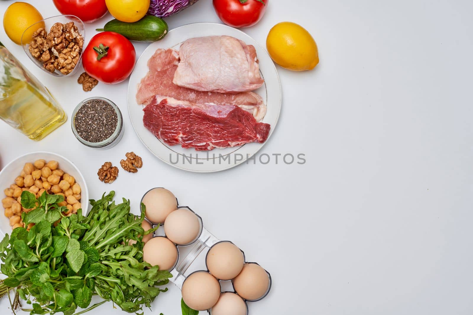 food that includes meat, eggs, vegetables, nuts and other items on a white background with space for text