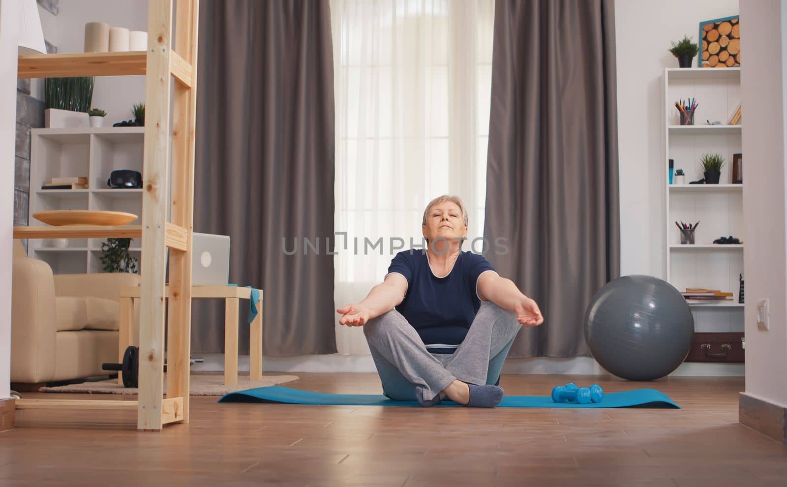 Senior woman relaxing in living room doing yoga. Active healthy lifestyle sporty old person training workout home wellness and indoor exercising