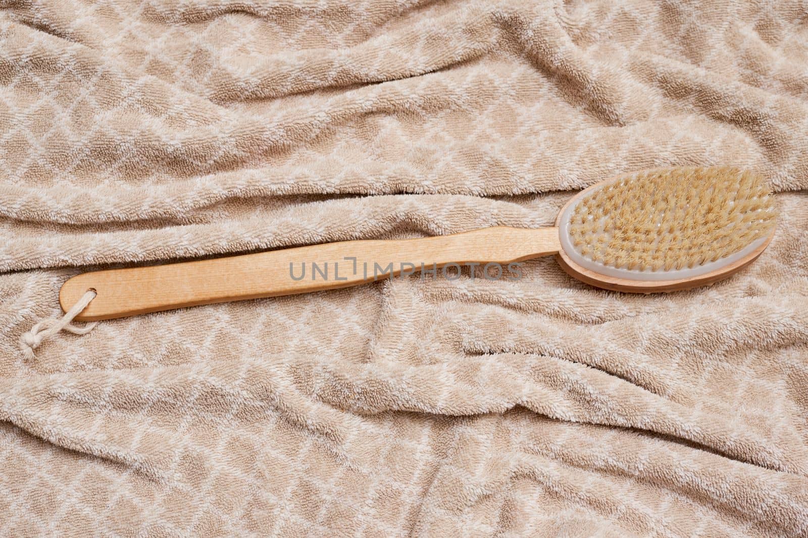 a wooden tooth brush on a bed with a white and beige blanket in the background, as seen from above