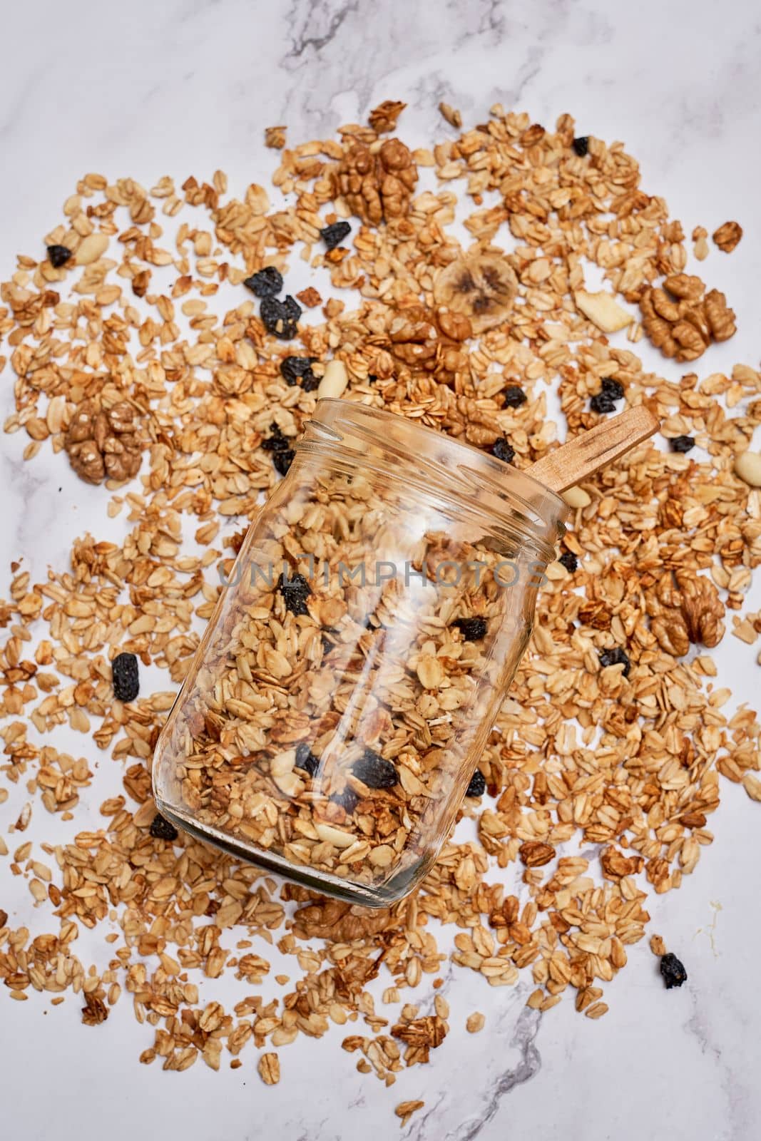 granos in a glass jar on a white marble countertopped with blueberries and almonds scattered around