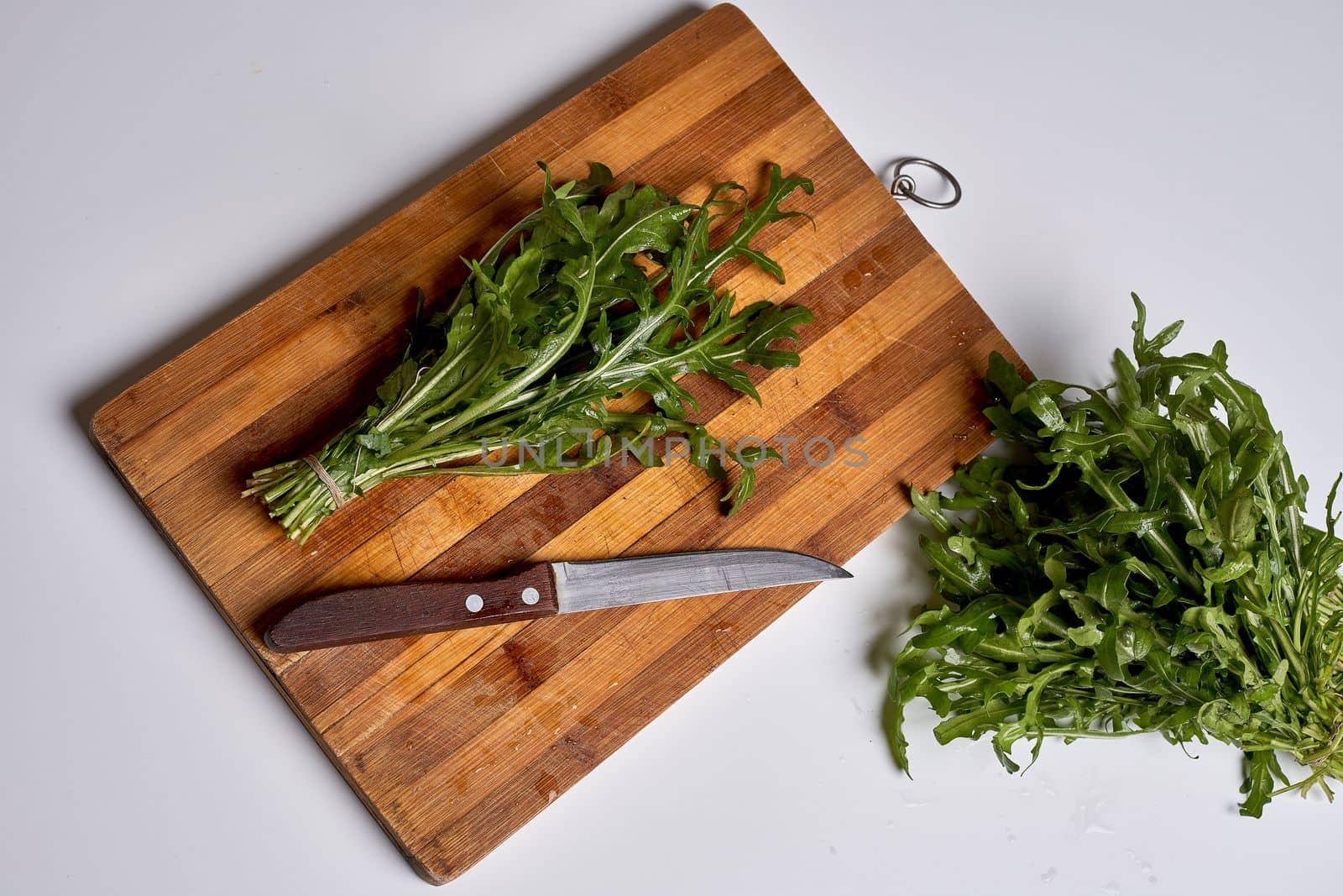 a cutting board with greens and a knife on it by golibtolibov