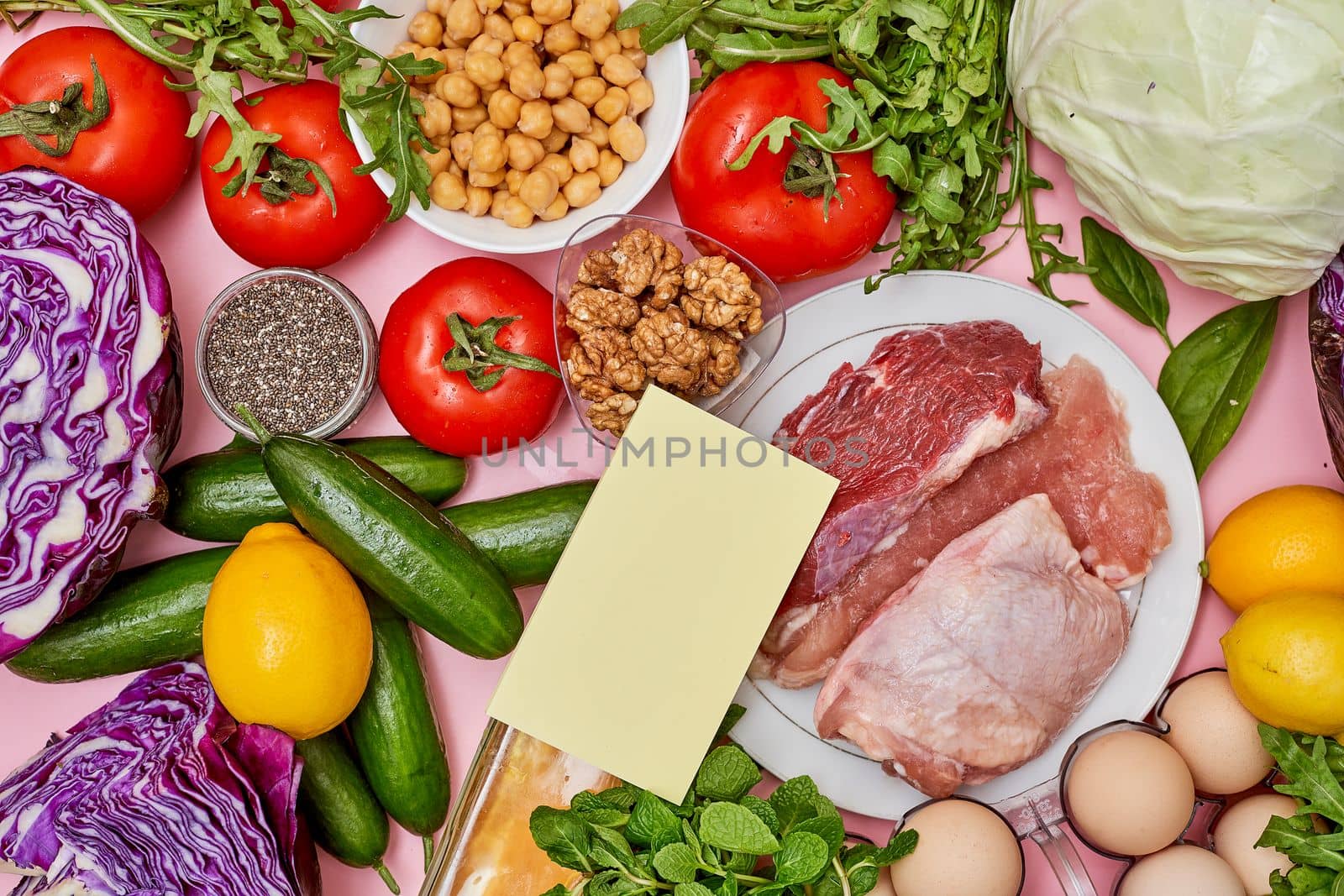 some food that is on a pink surface with vegetables, eggs, tomatoes, and other foods in the background