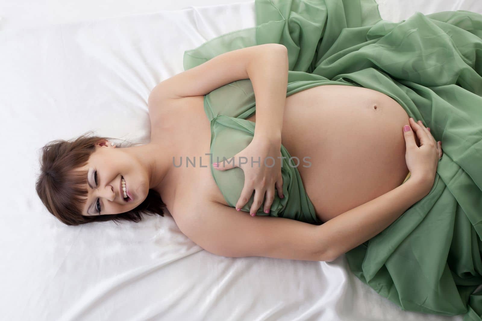 Happy pregnant woman lying in bed by rivertime