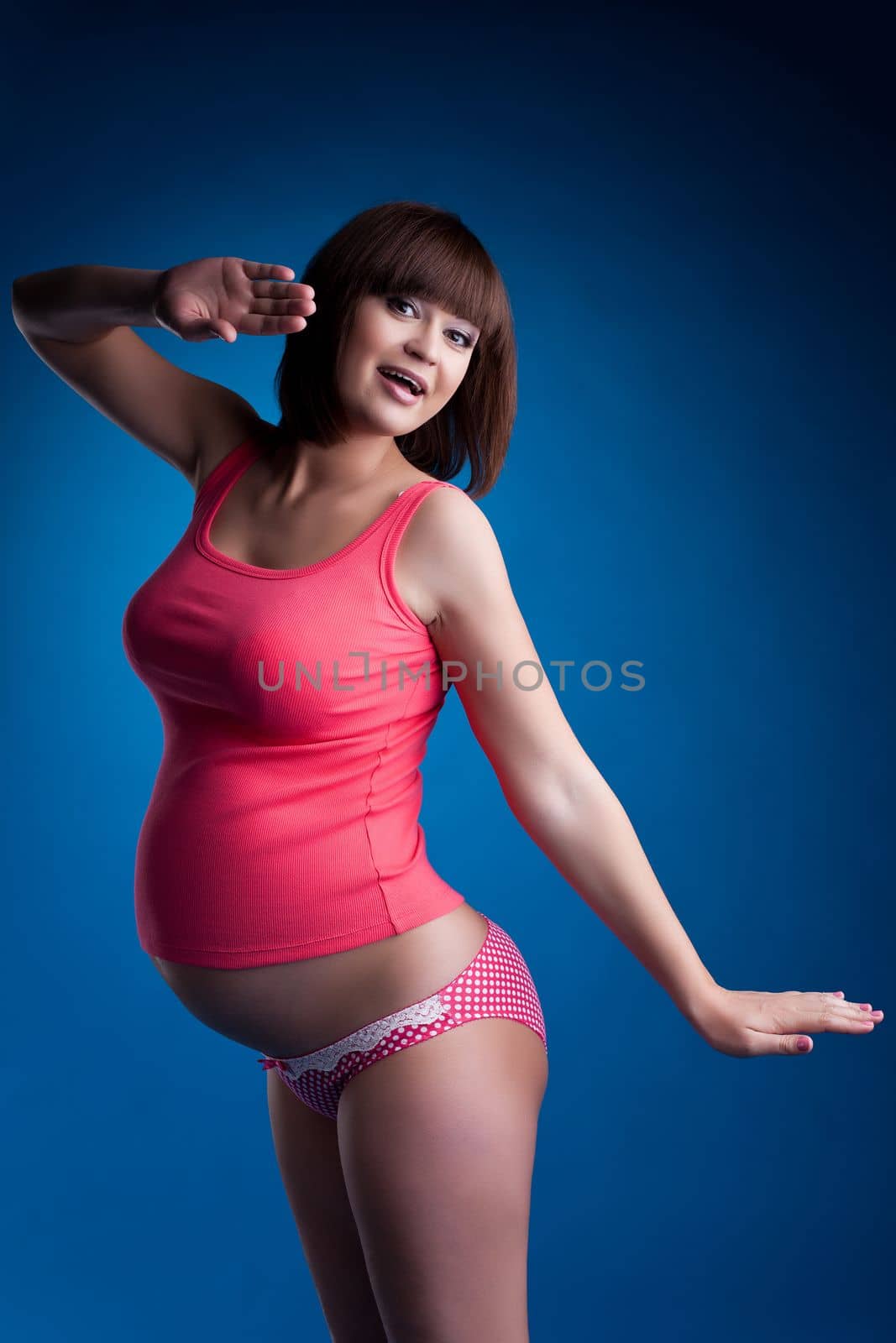 Pregnant woman in pink underwear on blue background