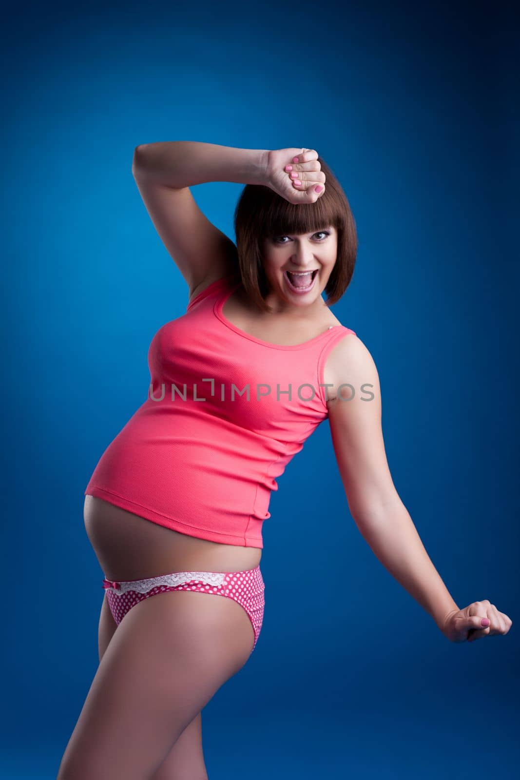 Studio portrait happy pregnant brunette young woman in pink underwear