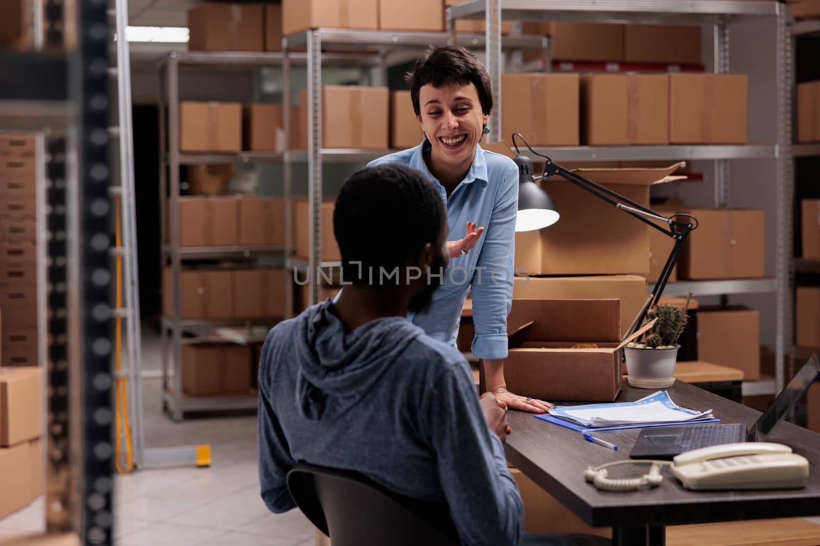 Storehouse workers having fun at job while preparing customers packages putting order in carton box by DCStudio